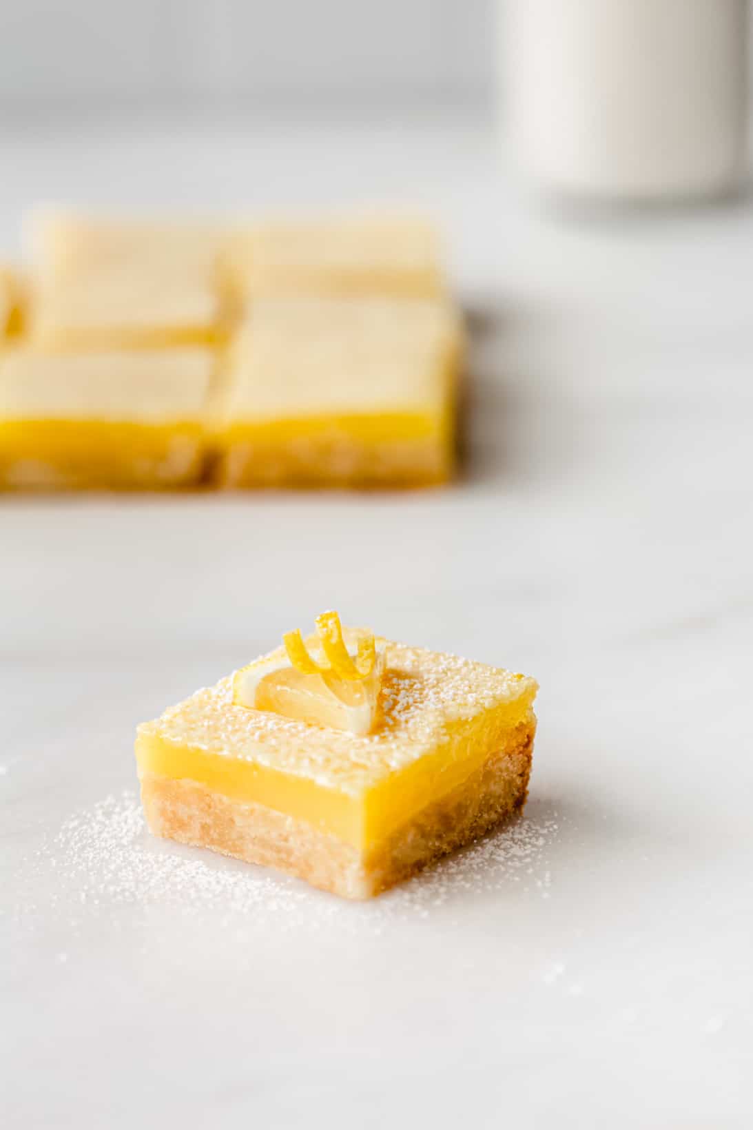 Lemon bars with milk in the background. 