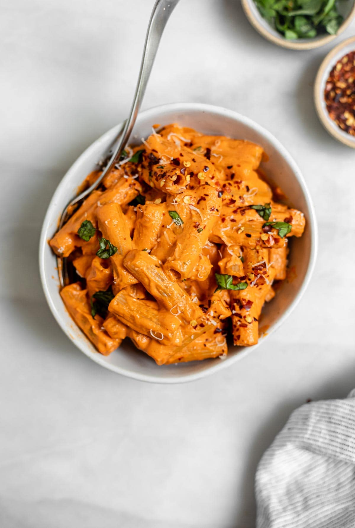 Vegan roasted red pepper pasta in a bowl with basil. 