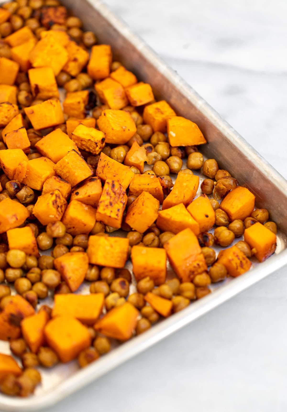 Roasted sweet potatoes and chickpeas on a baking tray.