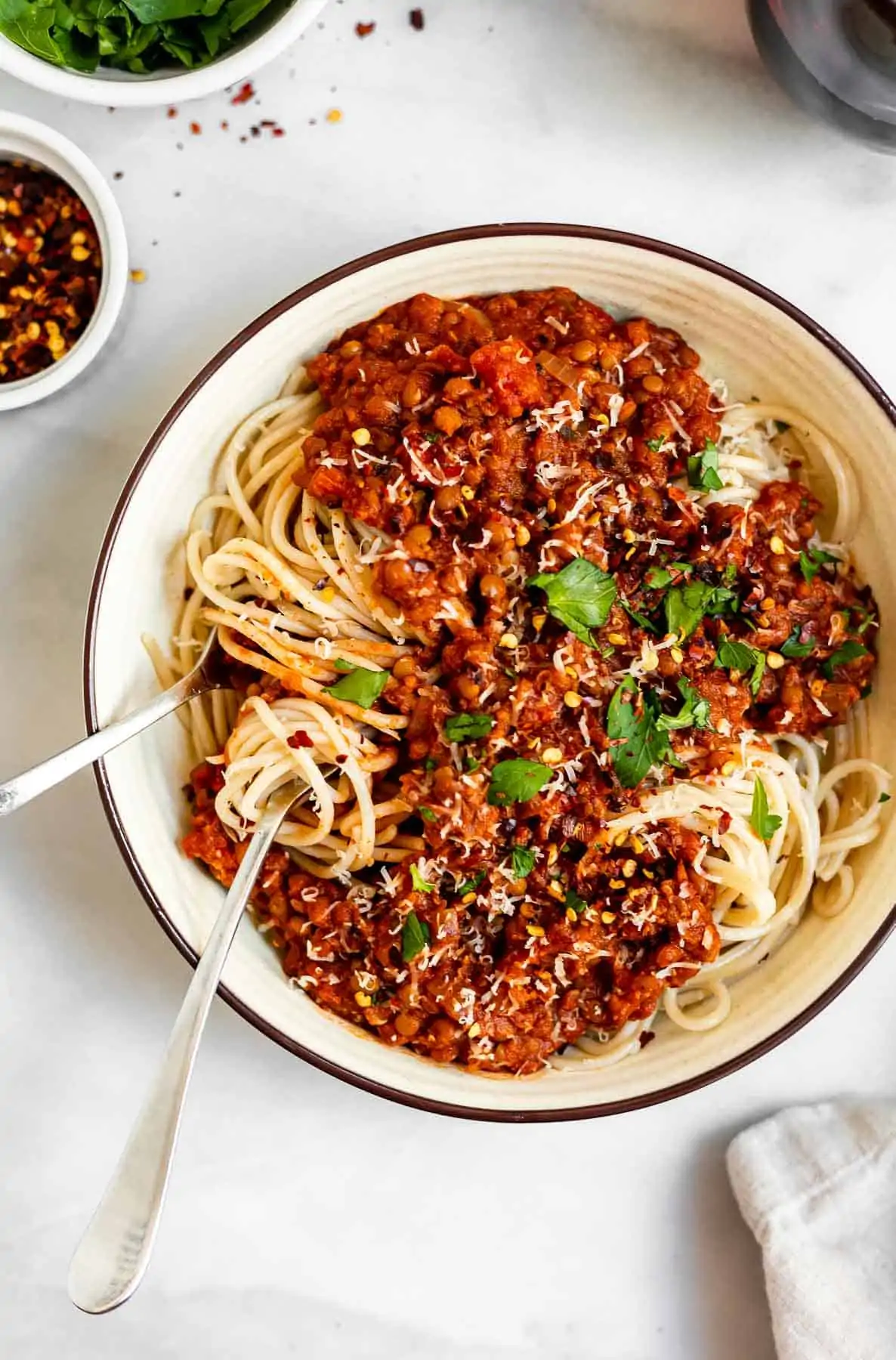 Vegan lentil bolognese in a bowl of spaghetti with parsley on top.