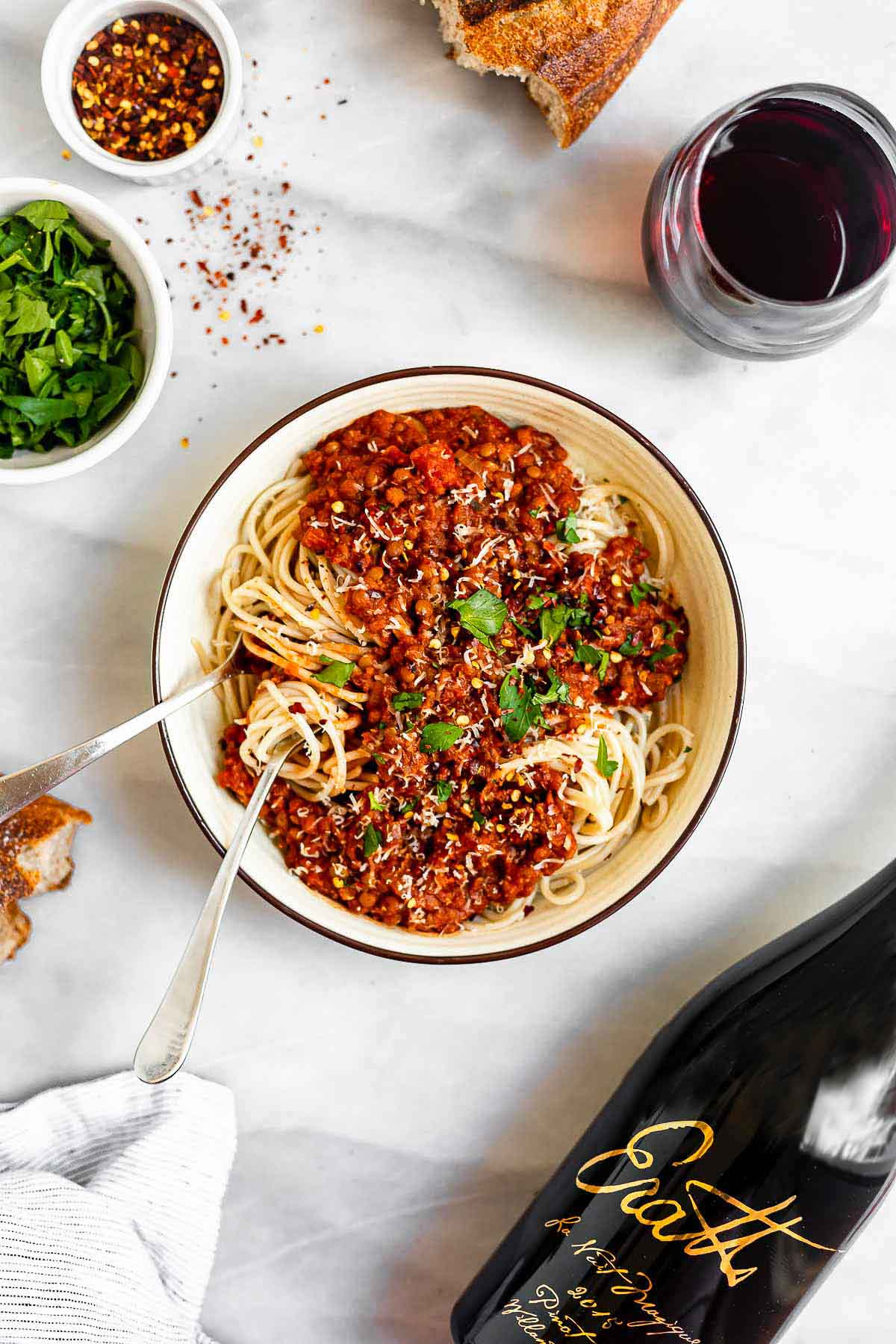 Final bolognese over spaghetti in a bowl with wine on the side.
