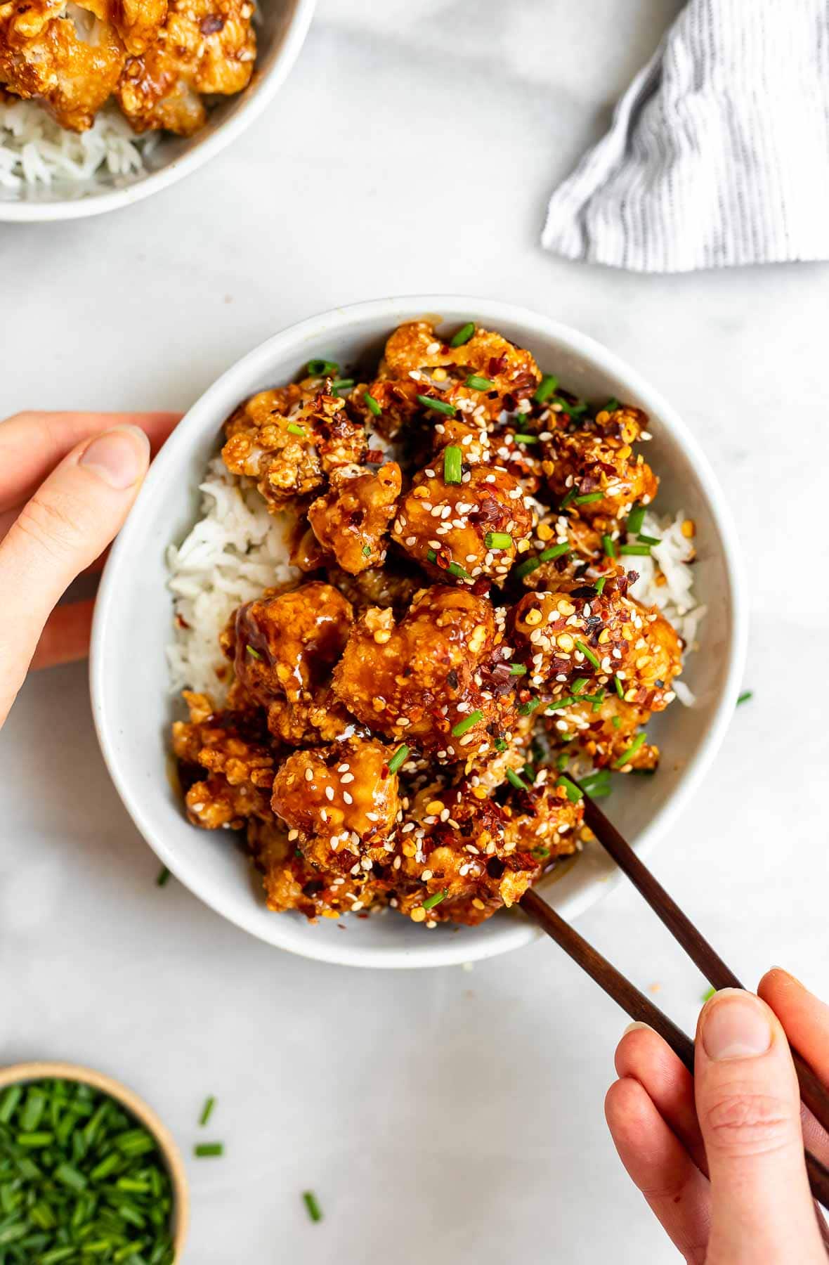 Vegan baked Sesame cauliflower in a bowl with rice underneath.