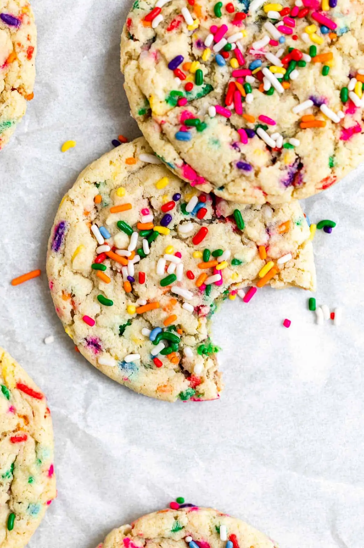 Funfetti sugar cookies stacked on each other on parchment paper. 