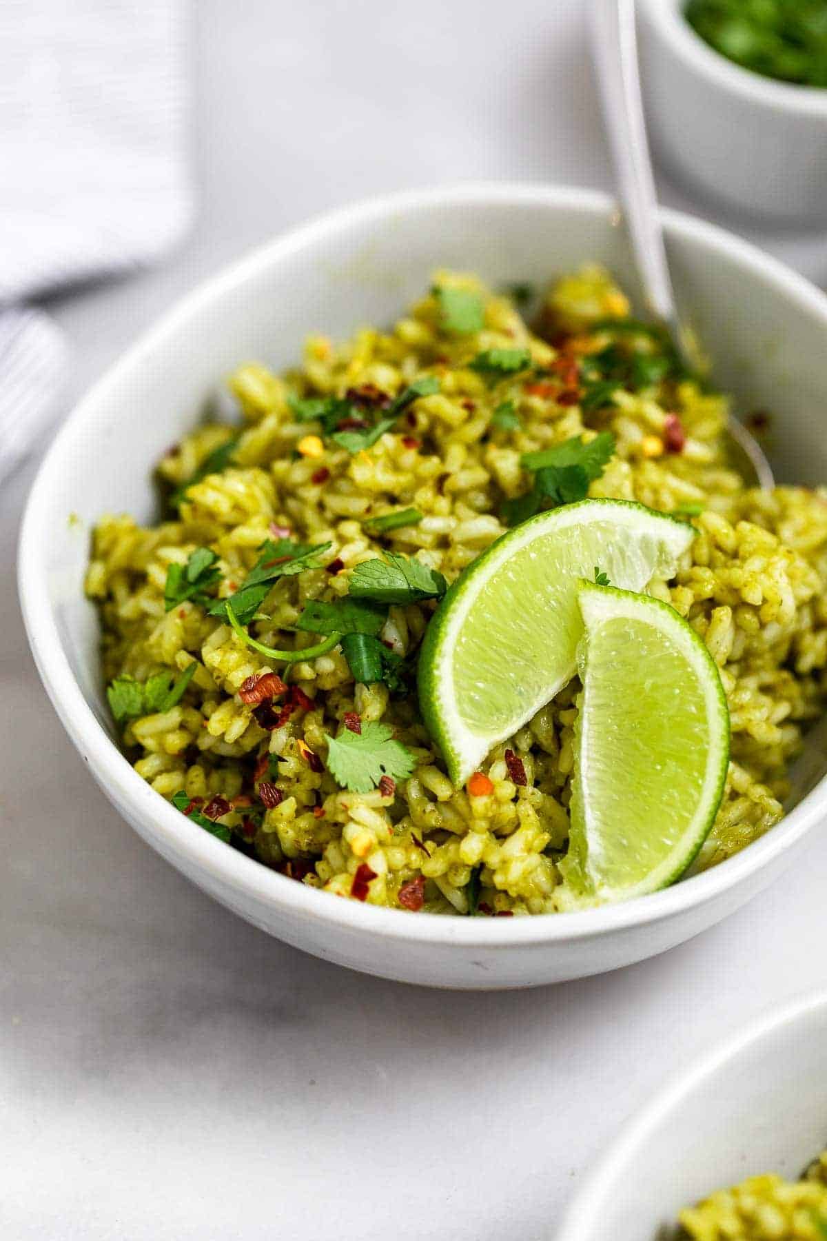Green rice in a small bowl tih lime wedges.