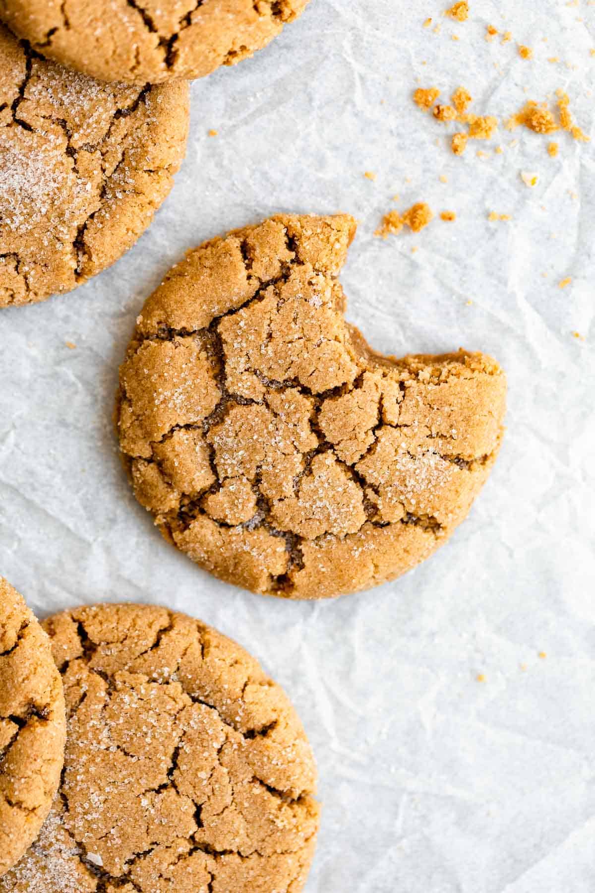 Peanut butter cookies on parchment paper with crumbs. 