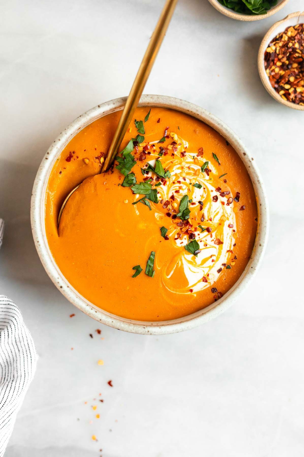 Vegan red lentil carrot soup with a spoon on the side.
