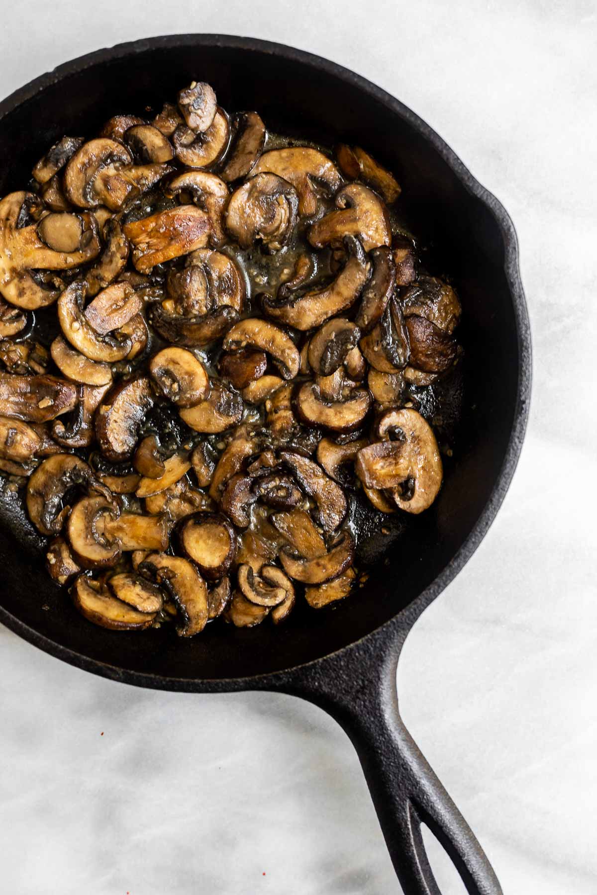 Mushrooms sauteed in a black pot with garlic.