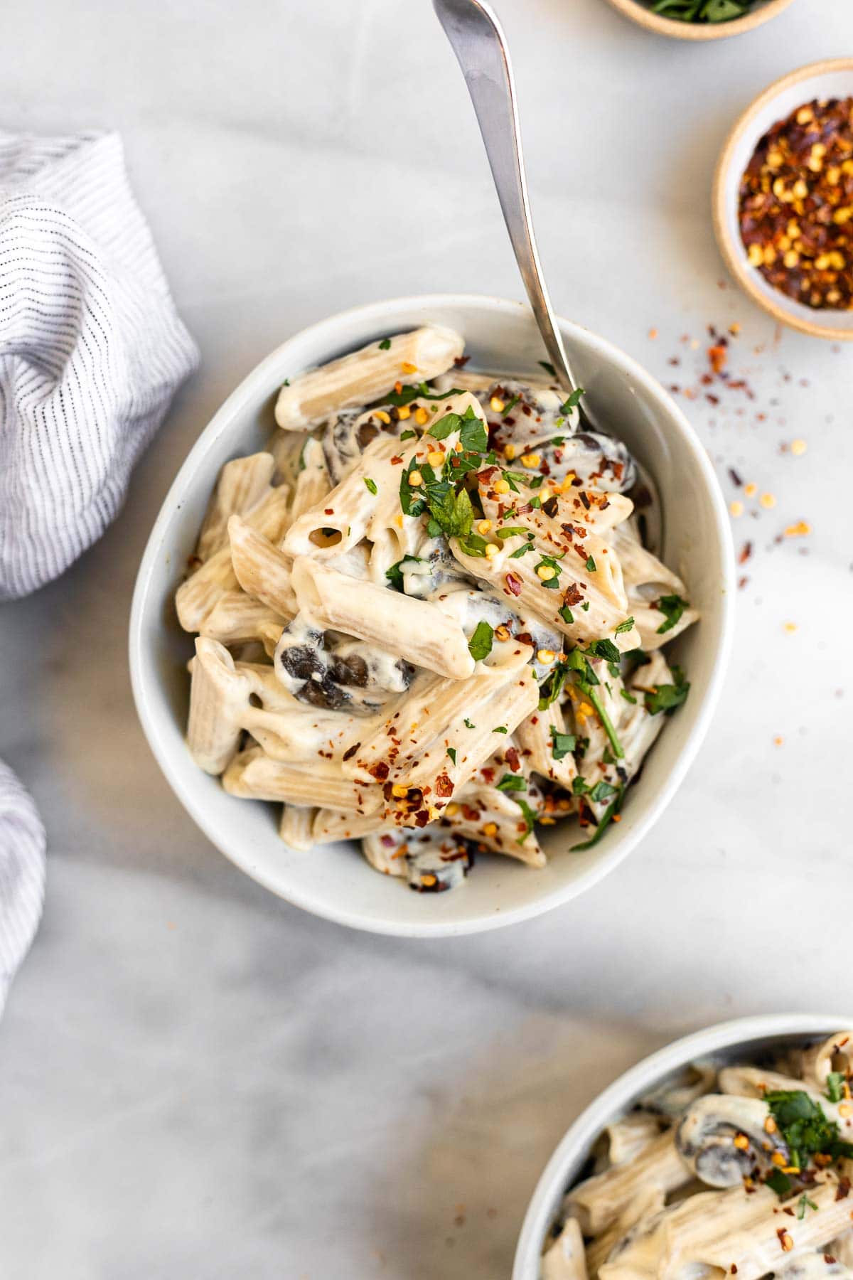 Two bowls of the cashew cream pasta with mushrooms and parsley.