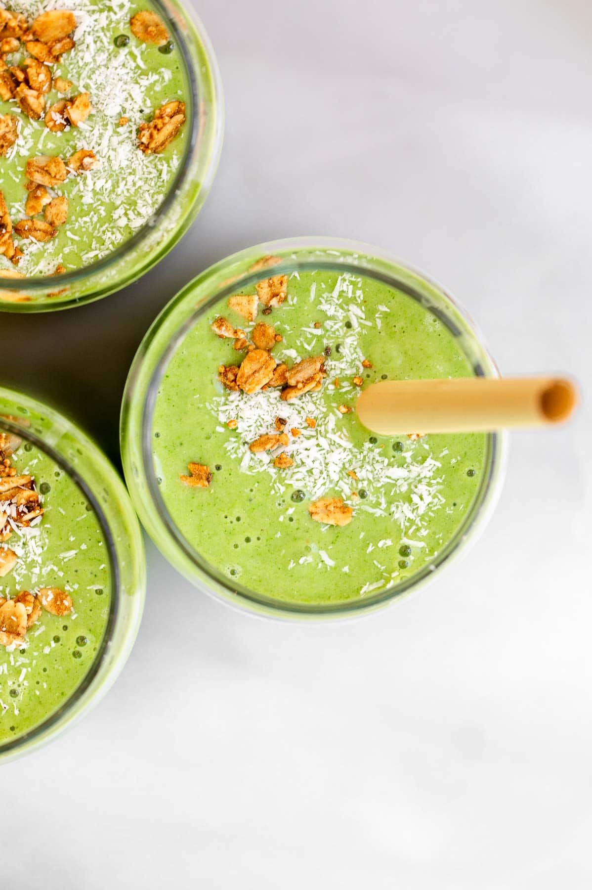 broccoli smoothie in three glasses with granola on top