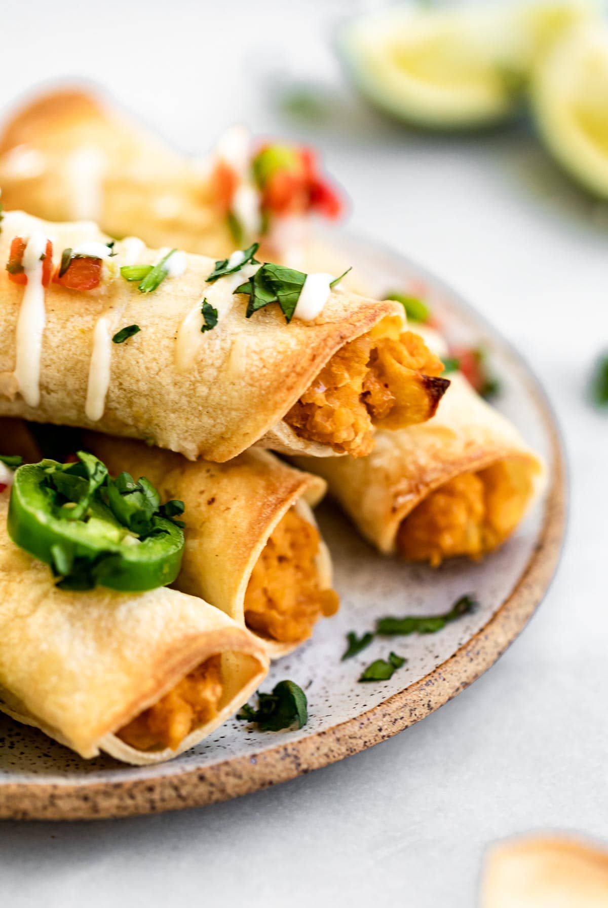 four taquitos sitting on a plate with cilantro