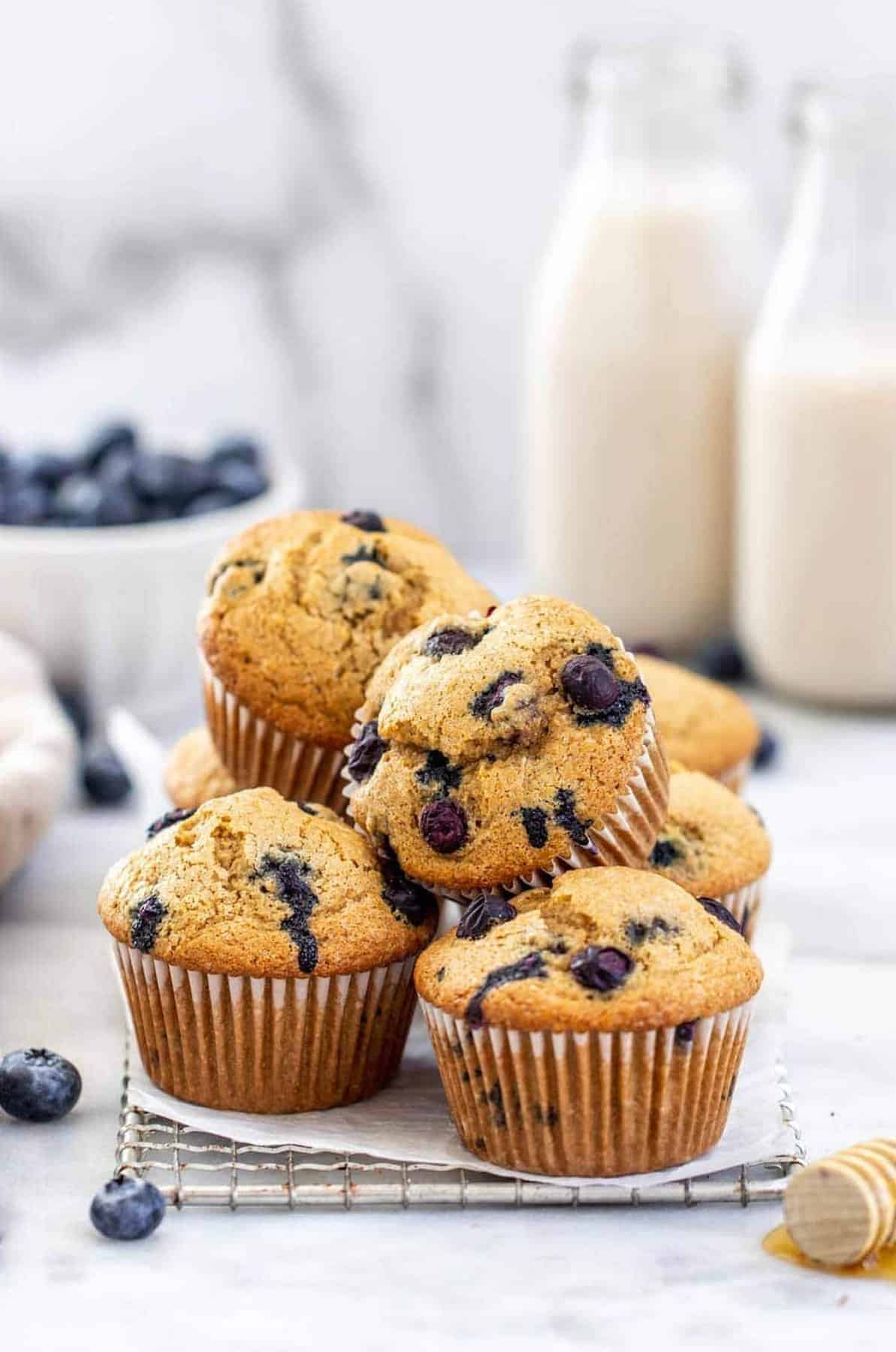 Gluten free blueberry muffins stacked with milk in the back.