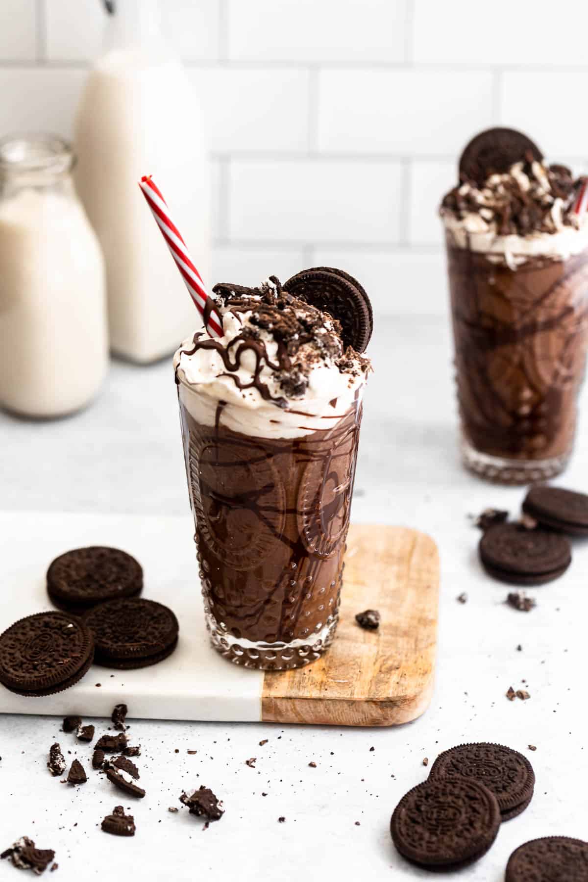 two vegan milkshakes in glasses with oreos and red straws.