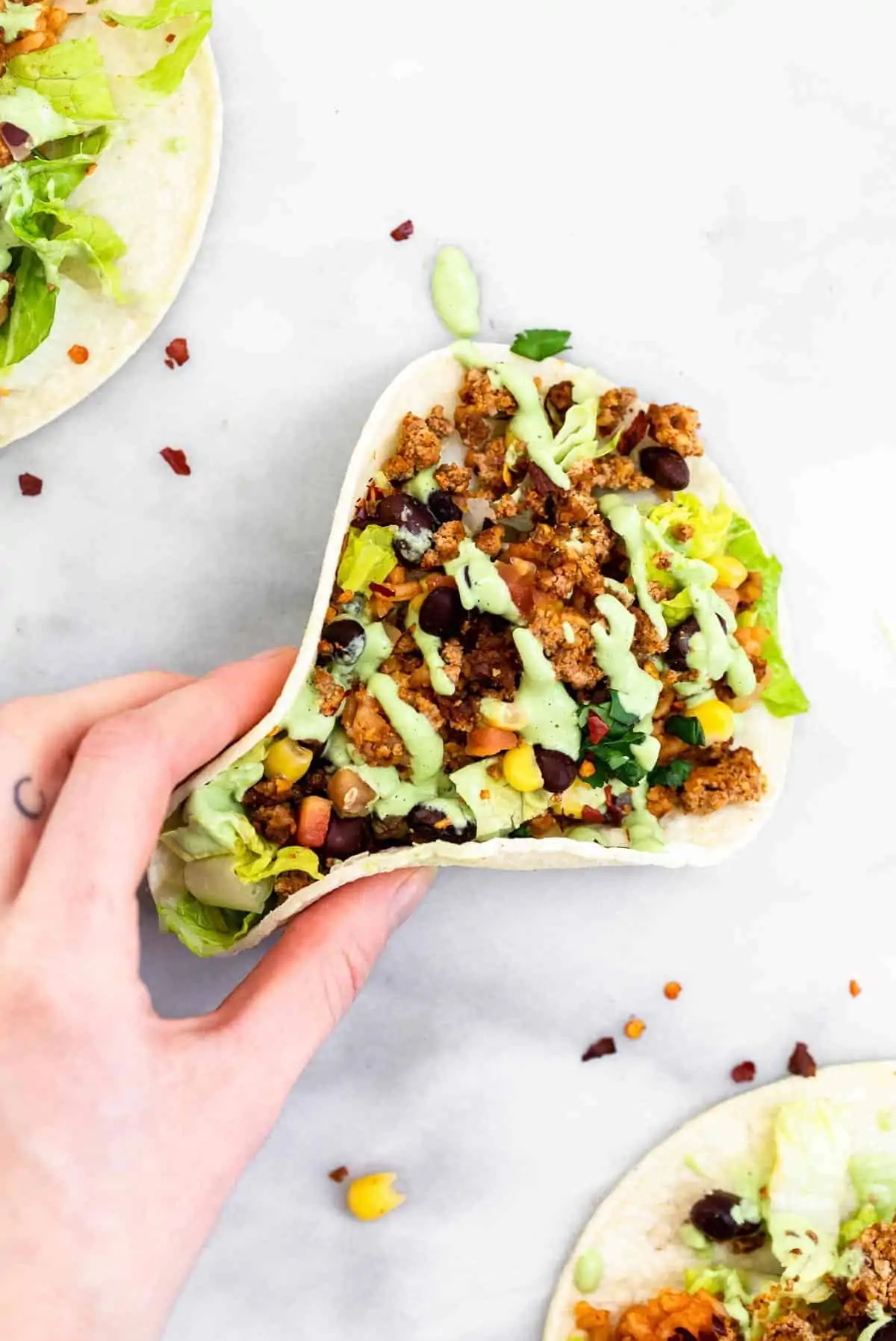 Hand grabbing a vegan taco with crema on top