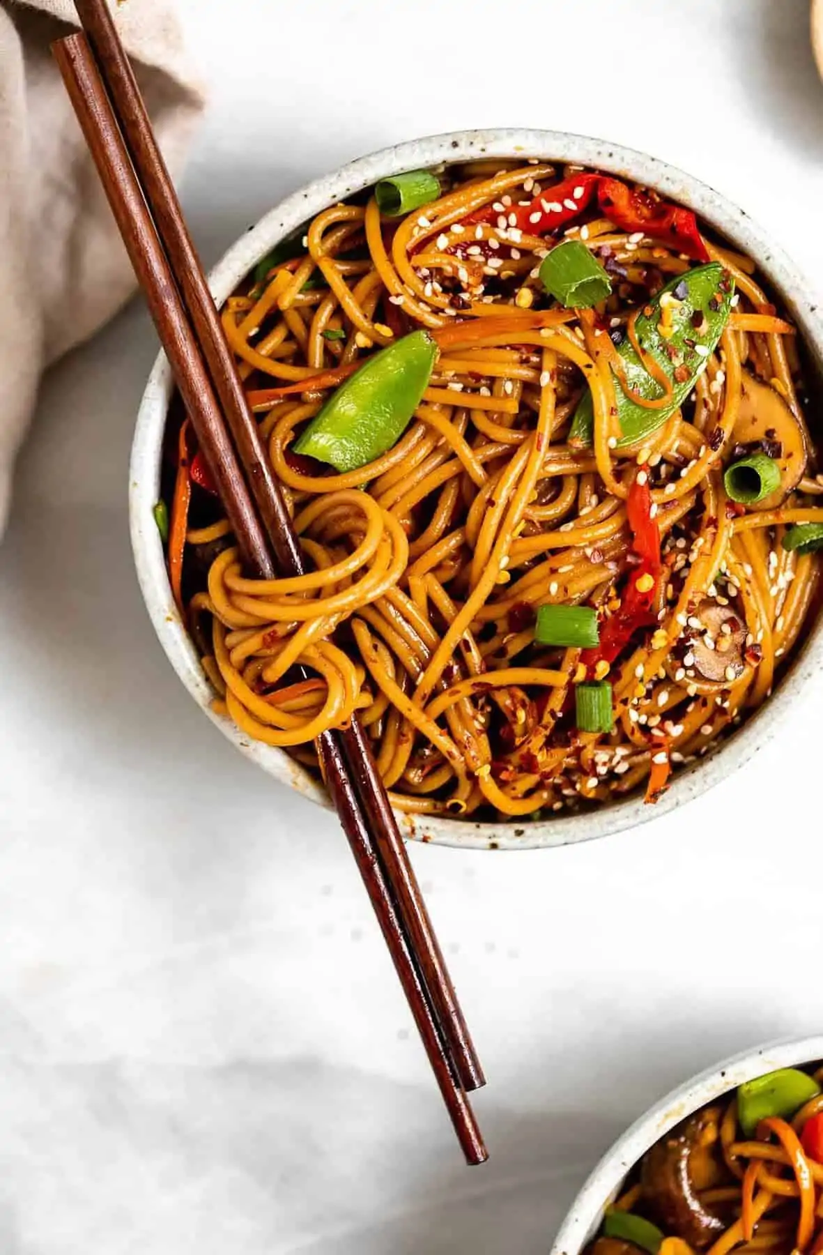 vegetable lo mein in a bowl with noodles wrapped around the chopsticks.
