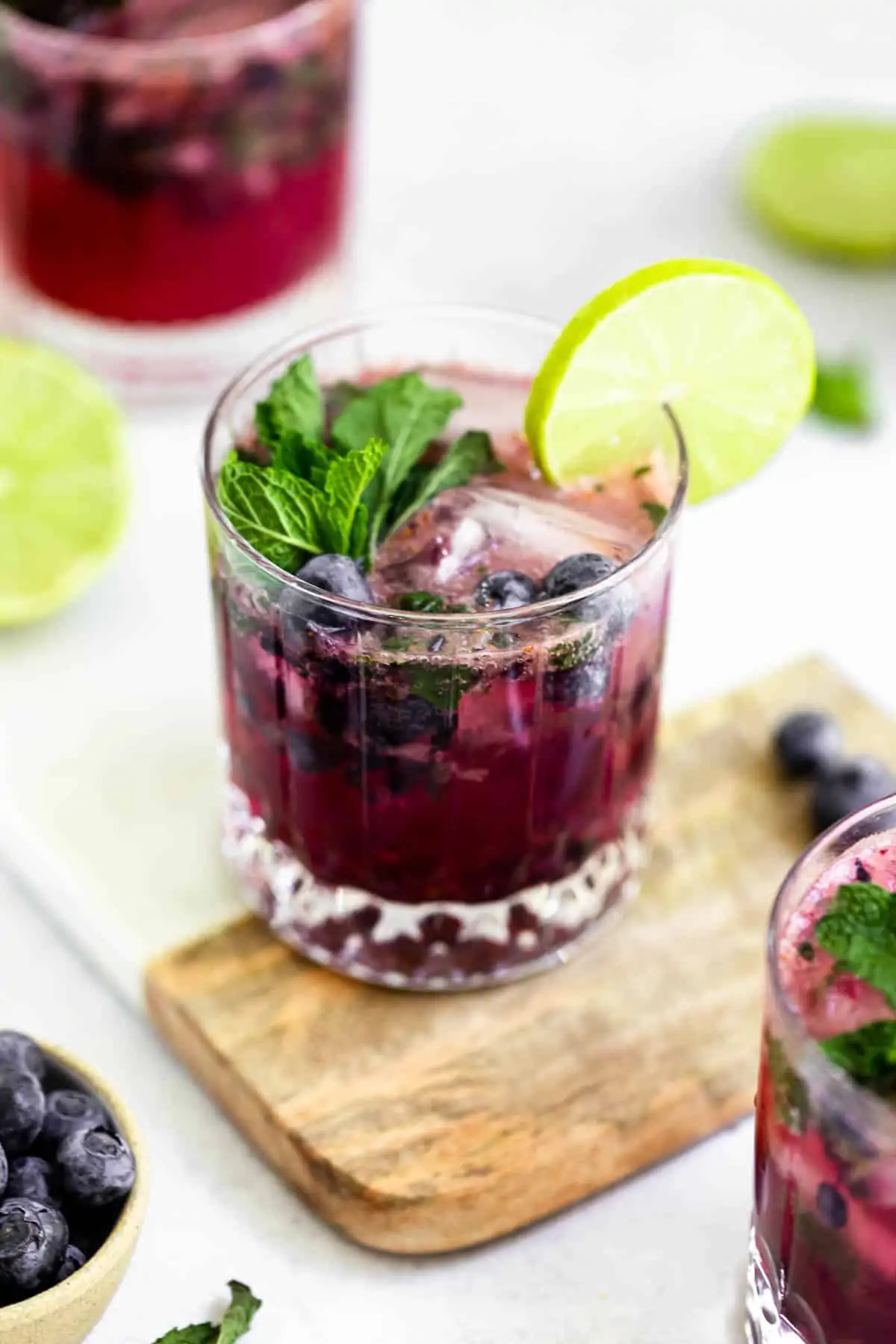 blueberry mojitos in three glasses with lime and mint
