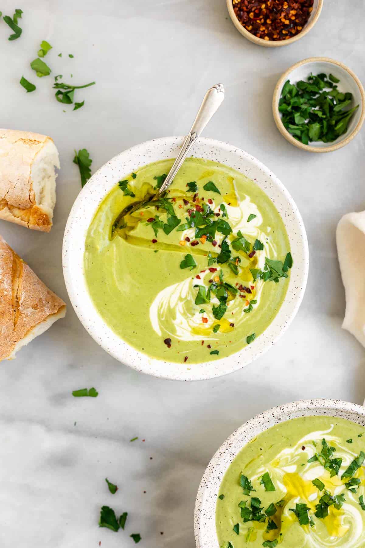 two bowls of vegan broccoli soup with fresh herbs