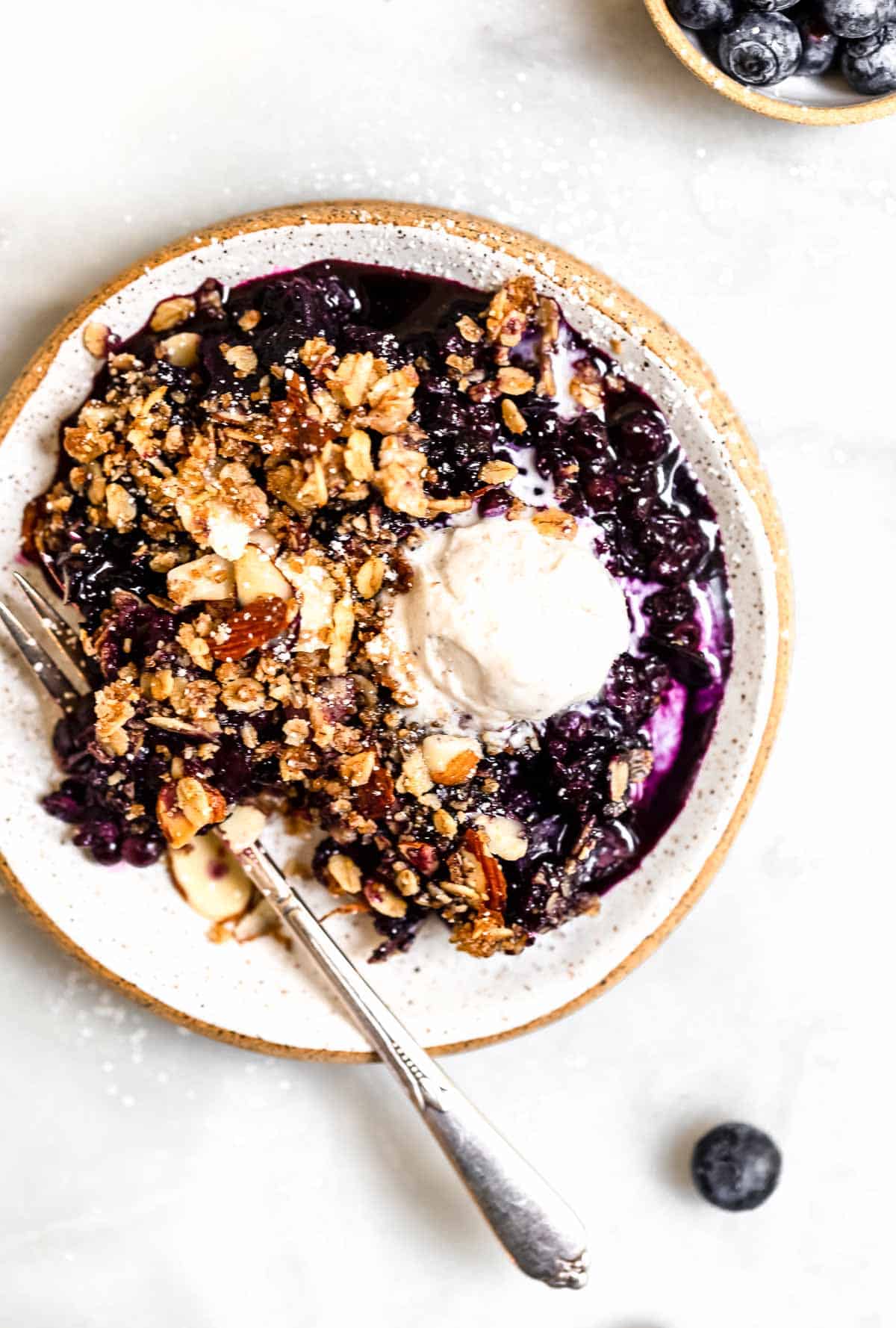 blueberry crisp on a plate with ice cream
