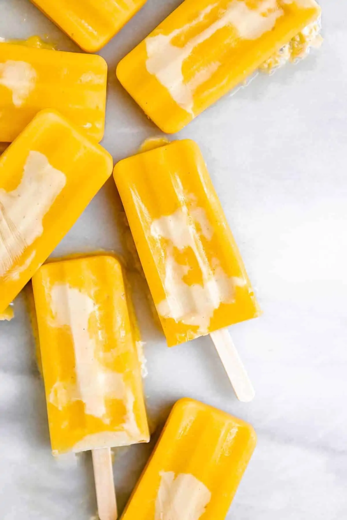 mango pineapple popsicles on a marble board