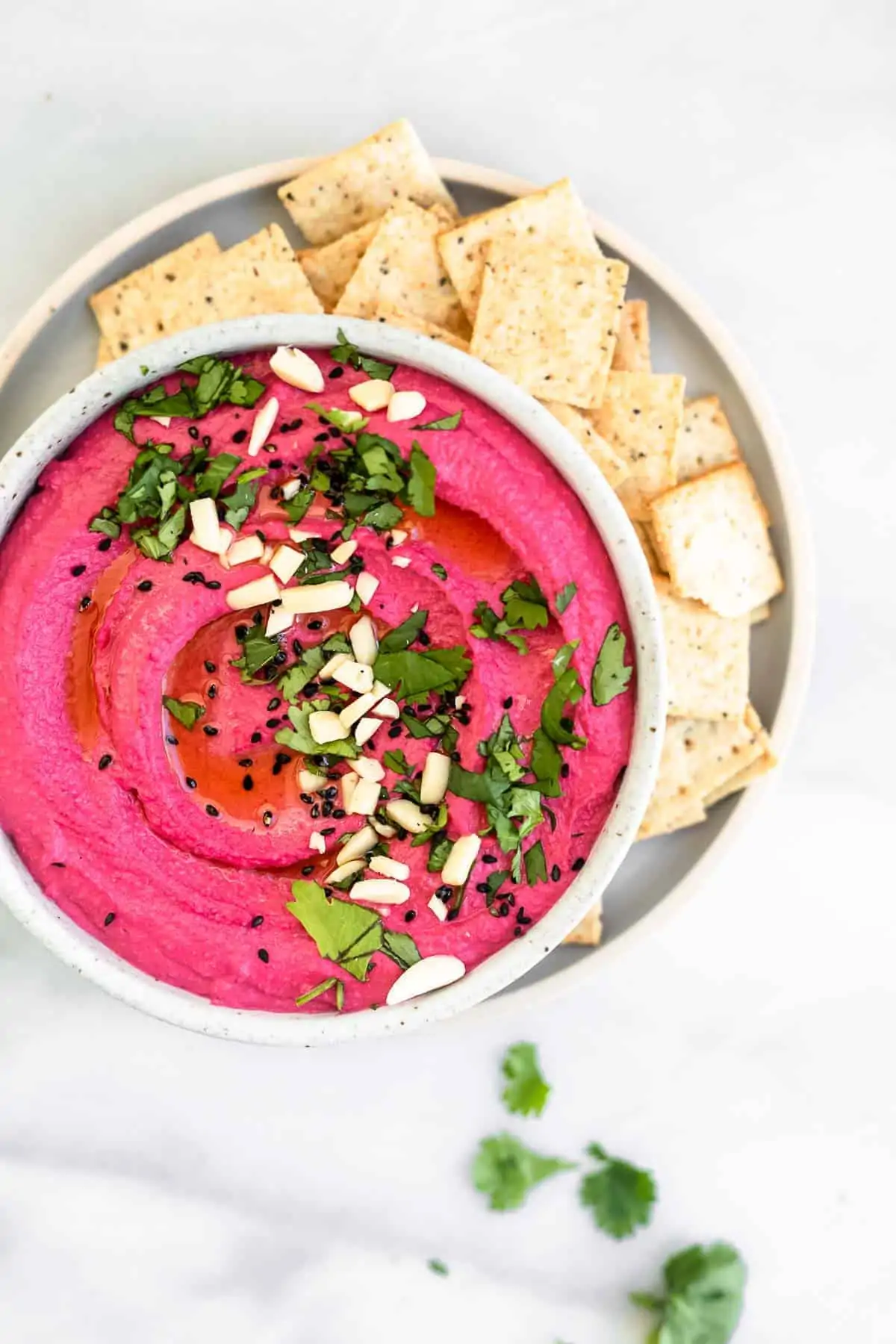 beet hummus in a bowl with crackers on the side