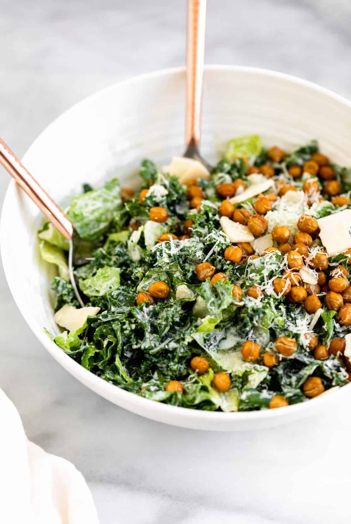 vegan kale caesar salad in a white bowl with crispy chickpea croutons