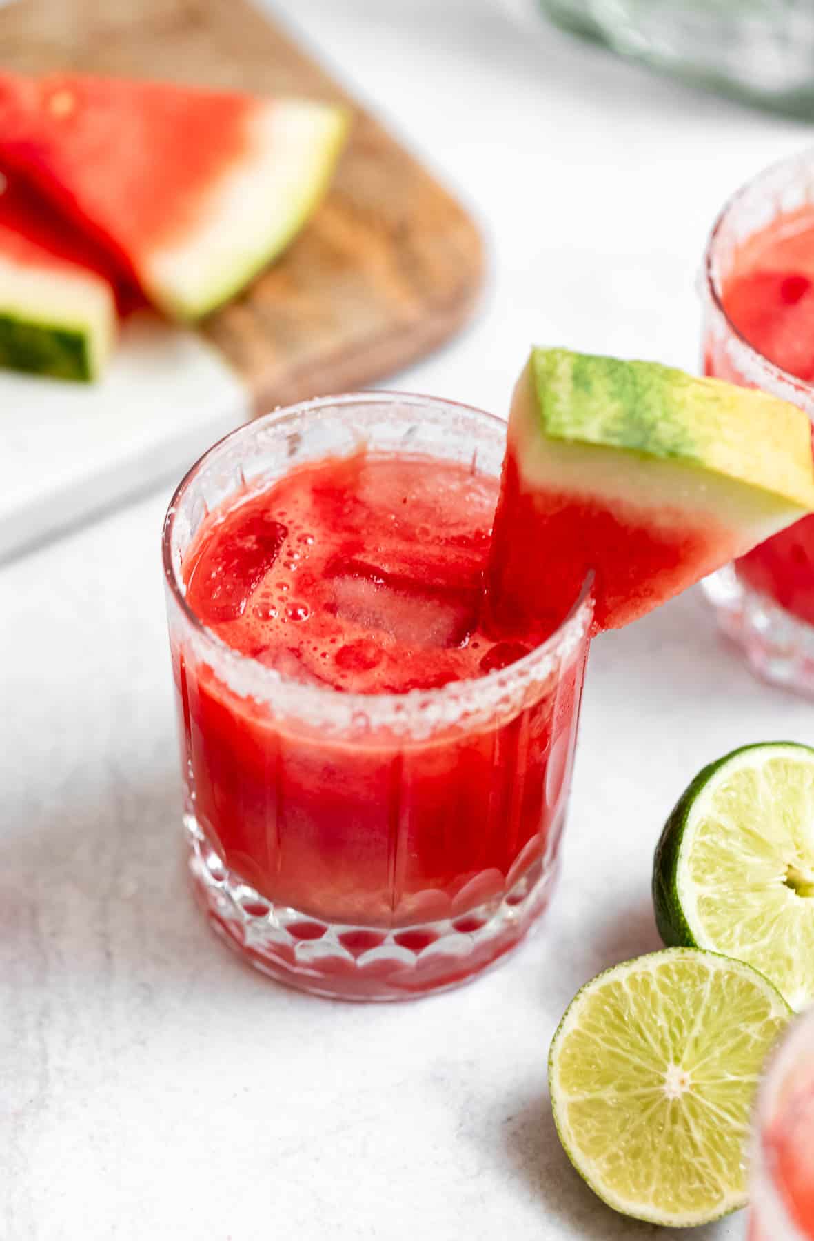 skinny watermelon margarita in a glass with lime wedges