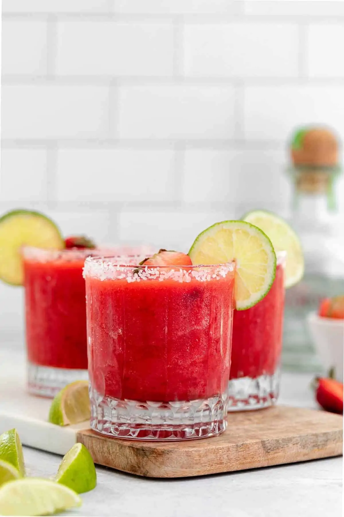 strawberry margarita in three glasses with lime wedges