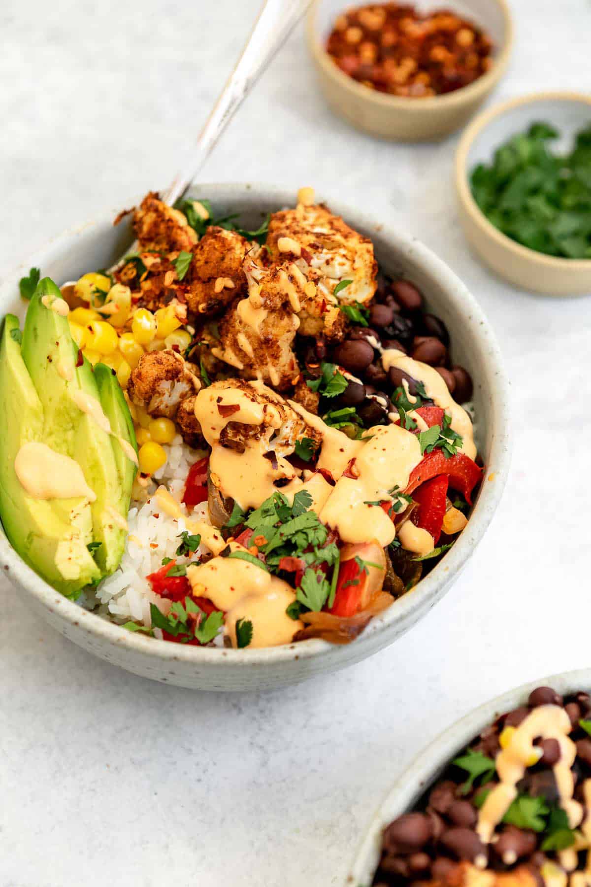 angled view of the vegan burrito bowl with bell peppers and roasted cauliflower
