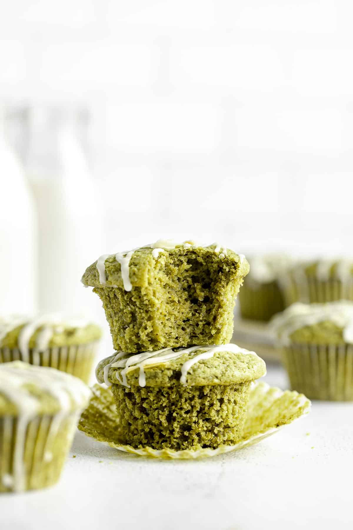 two matcha muffins stacked on each other with a bite taken out