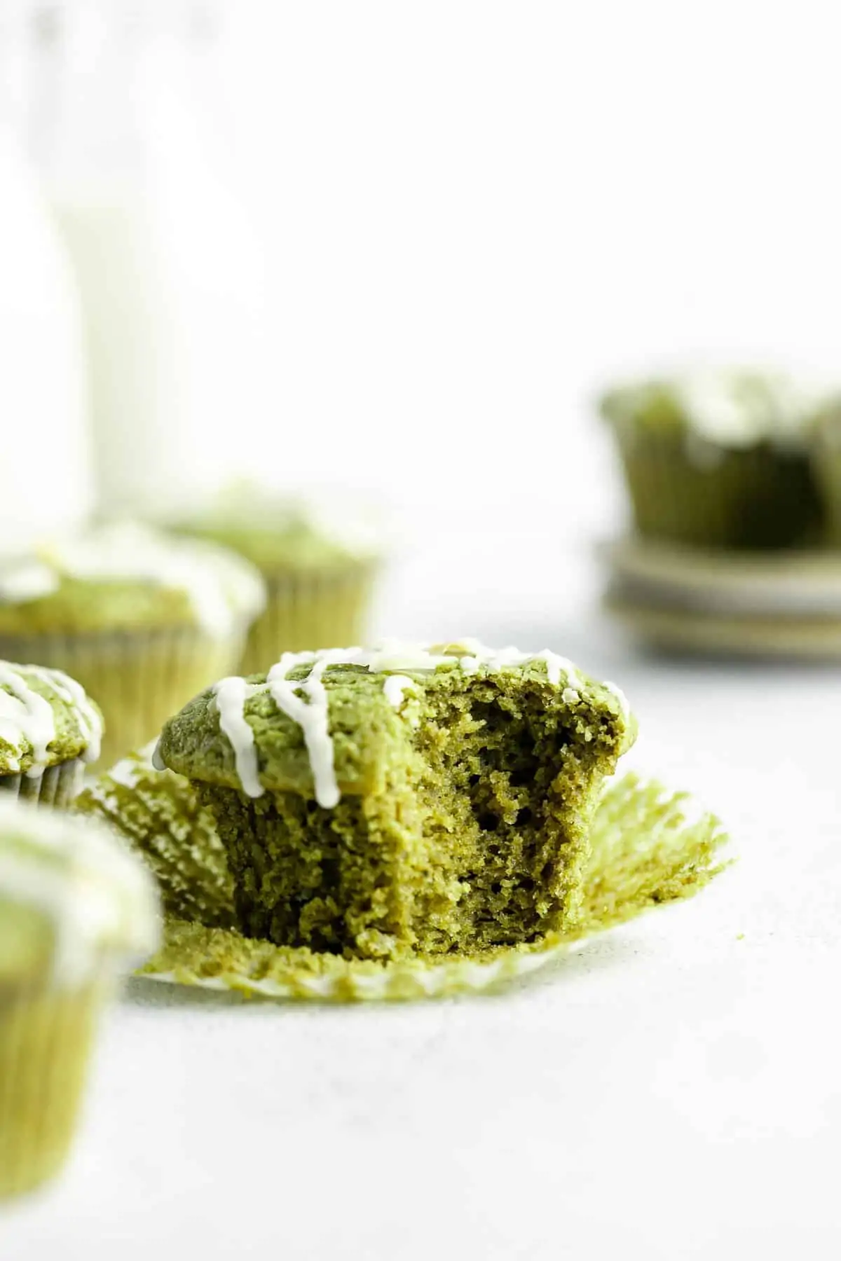 matcha muffins with one bite taken out to show fluffy texture