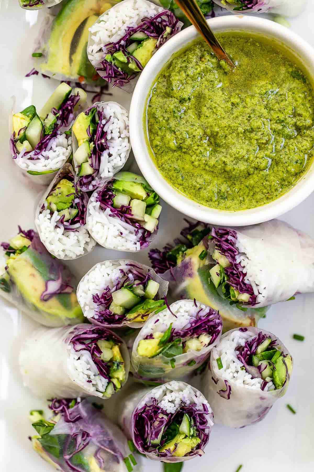 vegan summer rolls on a white board with pesto sauce