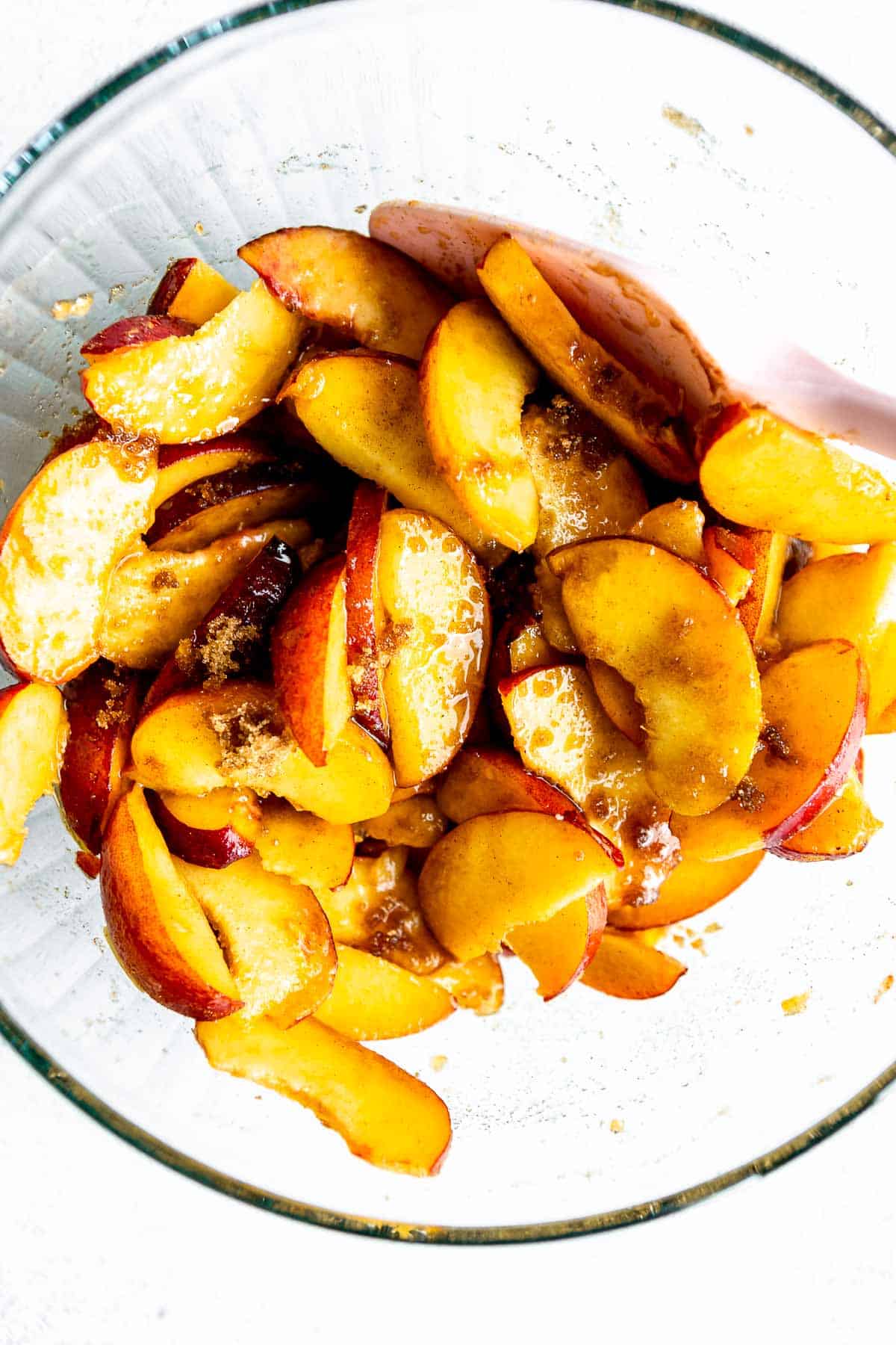 sliced peaches in a bowl with sugar on top