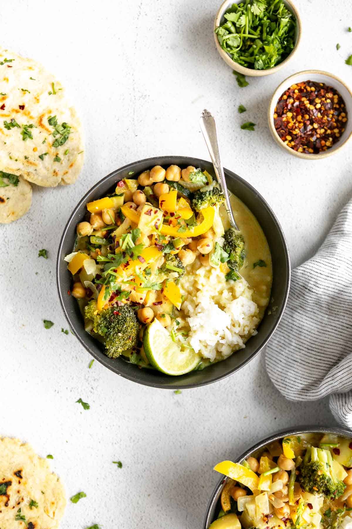 two bowls of the vegan thai green curry with naan and white rice