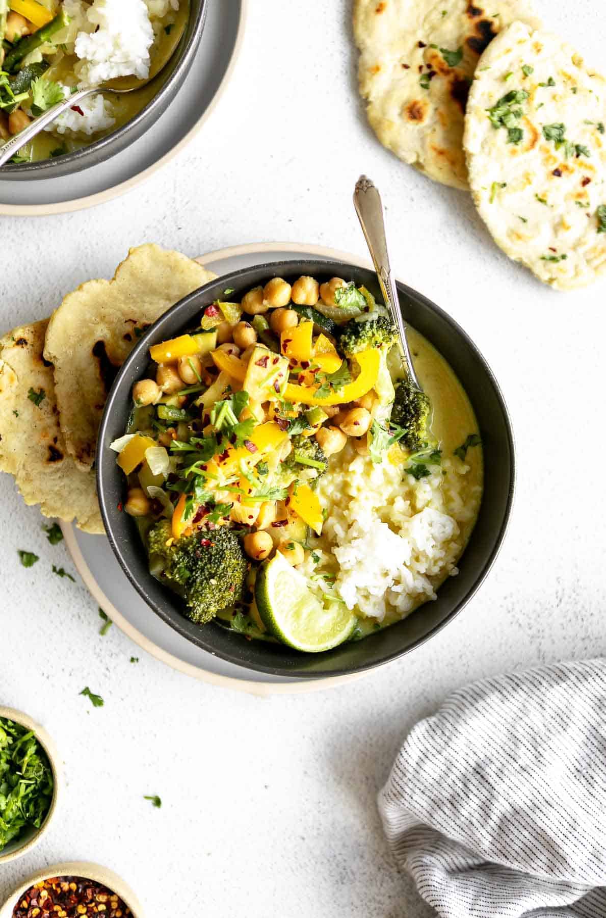 vegan thai green curry in a bowl with naan on the side