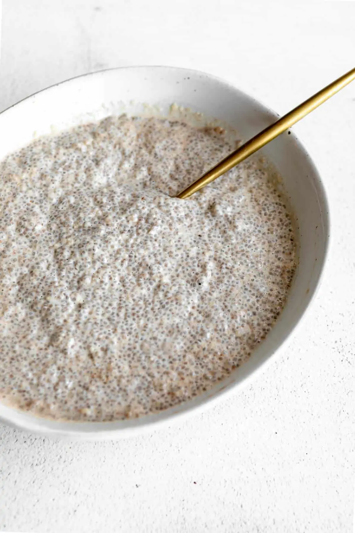 chia seed pudding in a bowl with a gold spoon