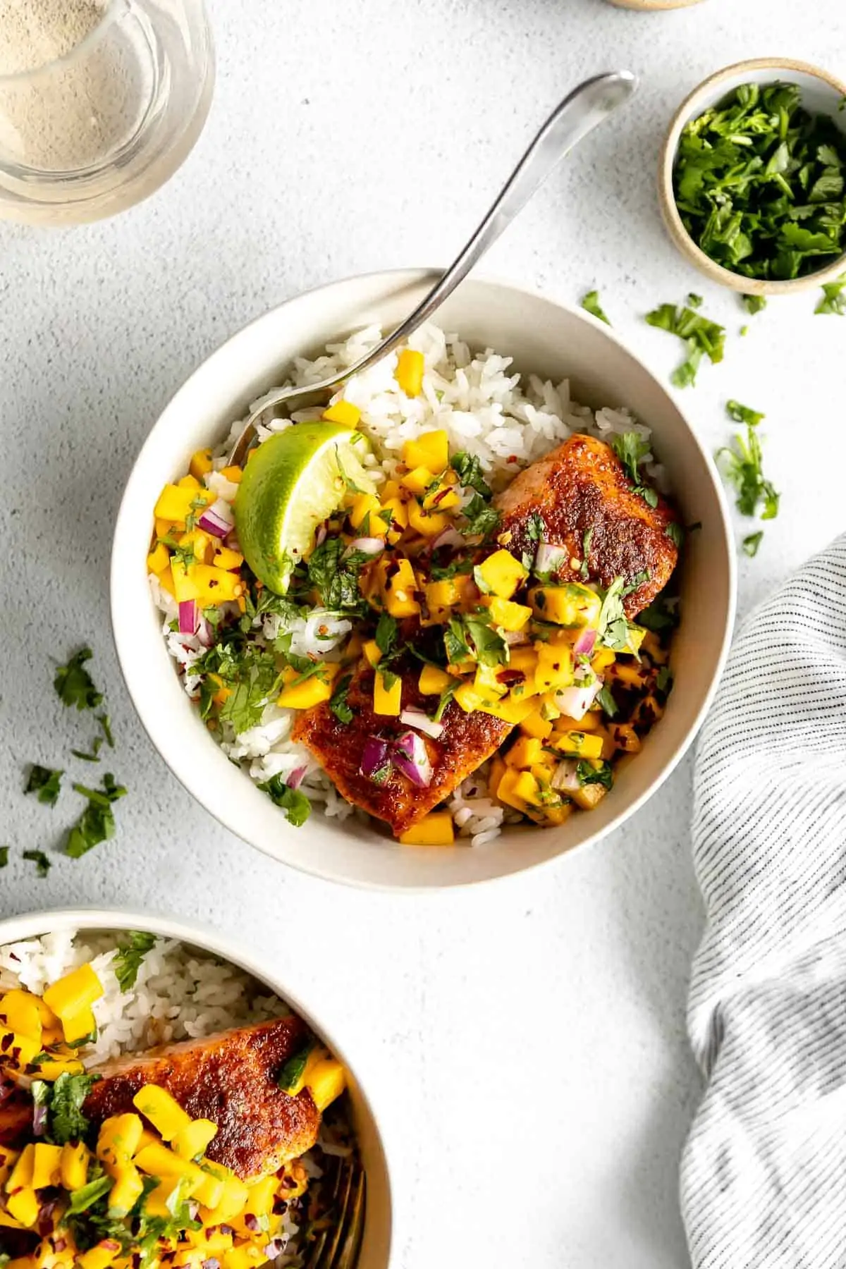 fish with mango salsa over rice in two white bowls