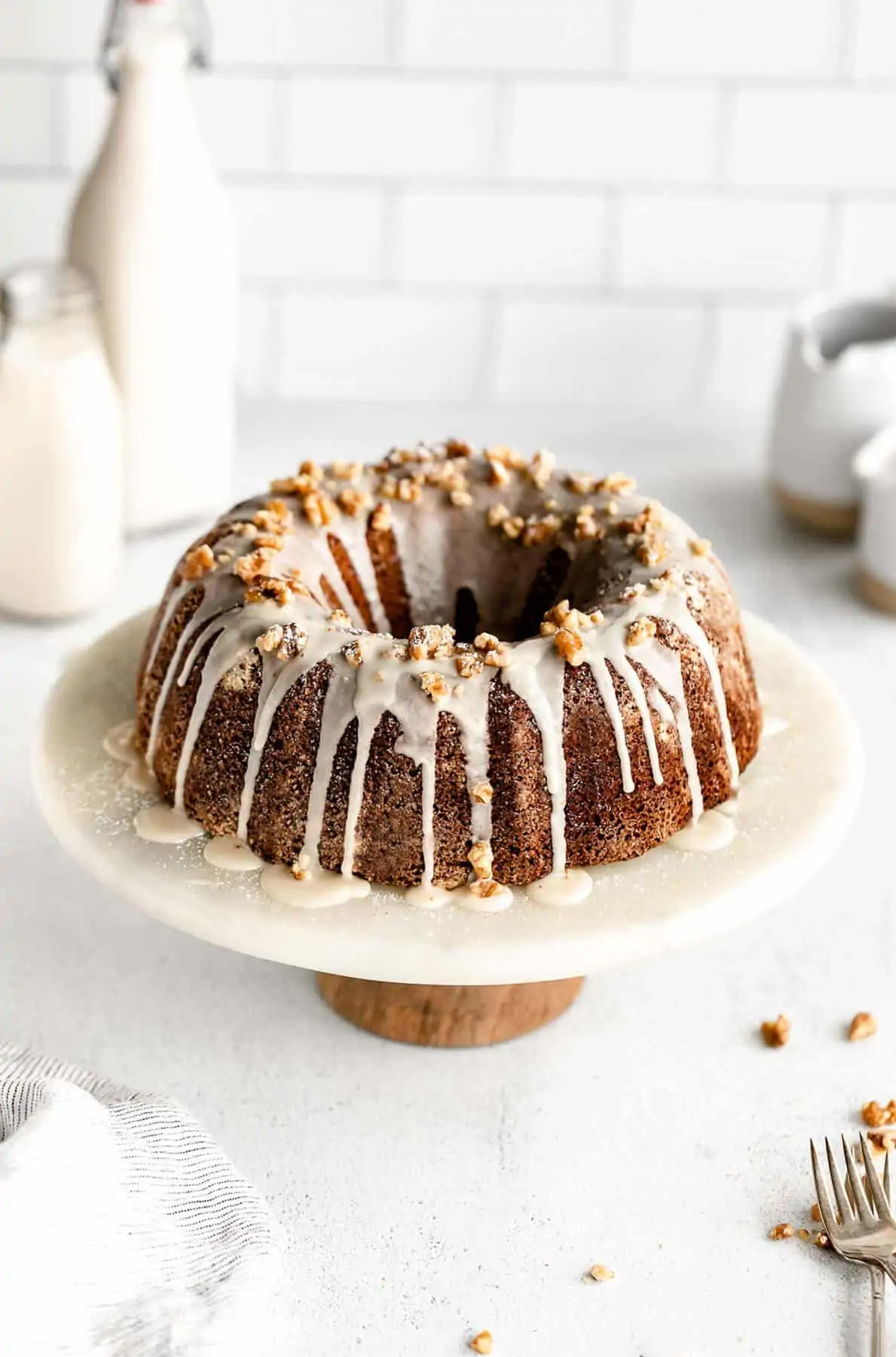 gluten free apple bundt cake on a cake stand with maple icing