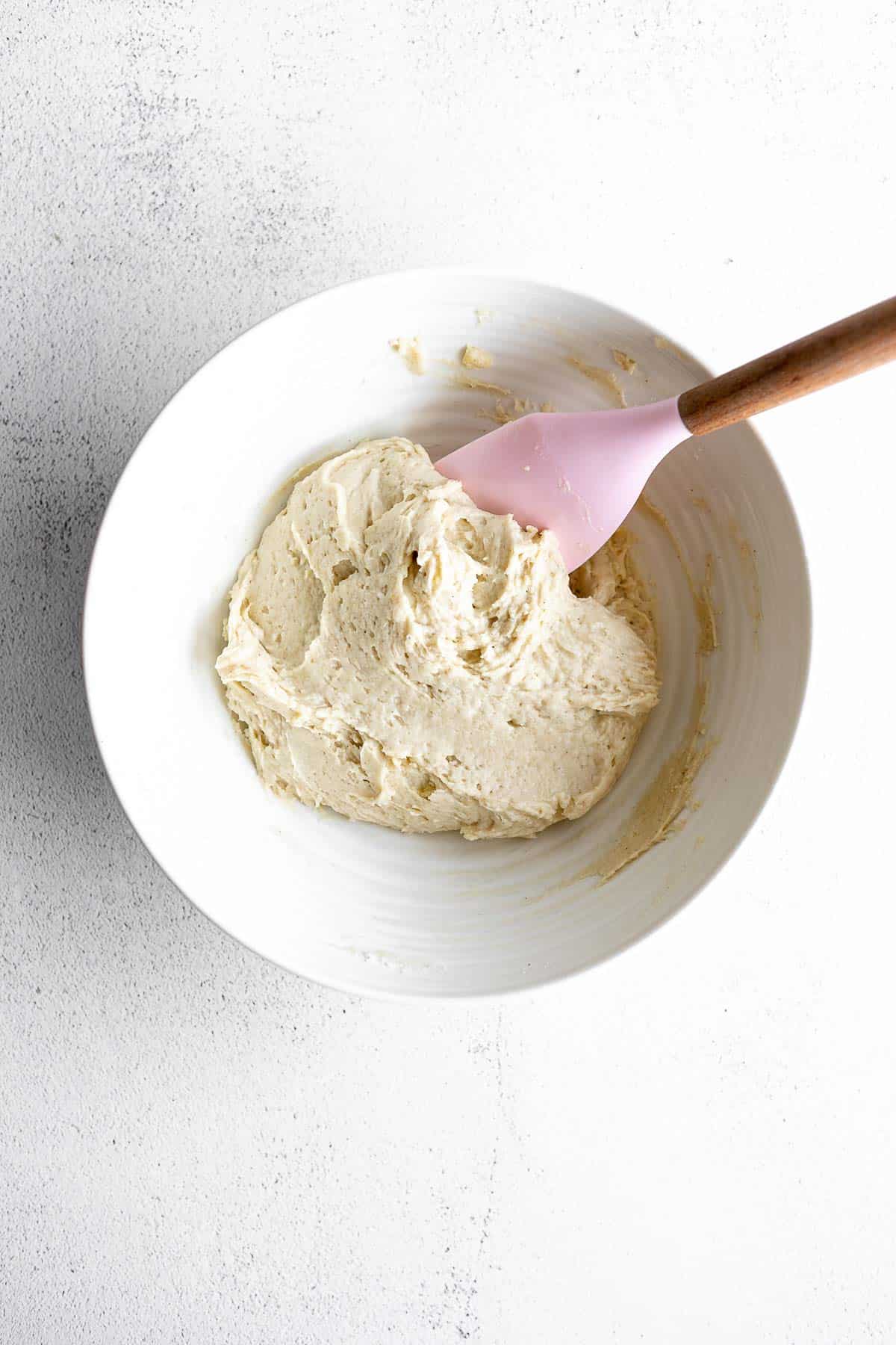 dough in a bowl with a wooden spoon on the side