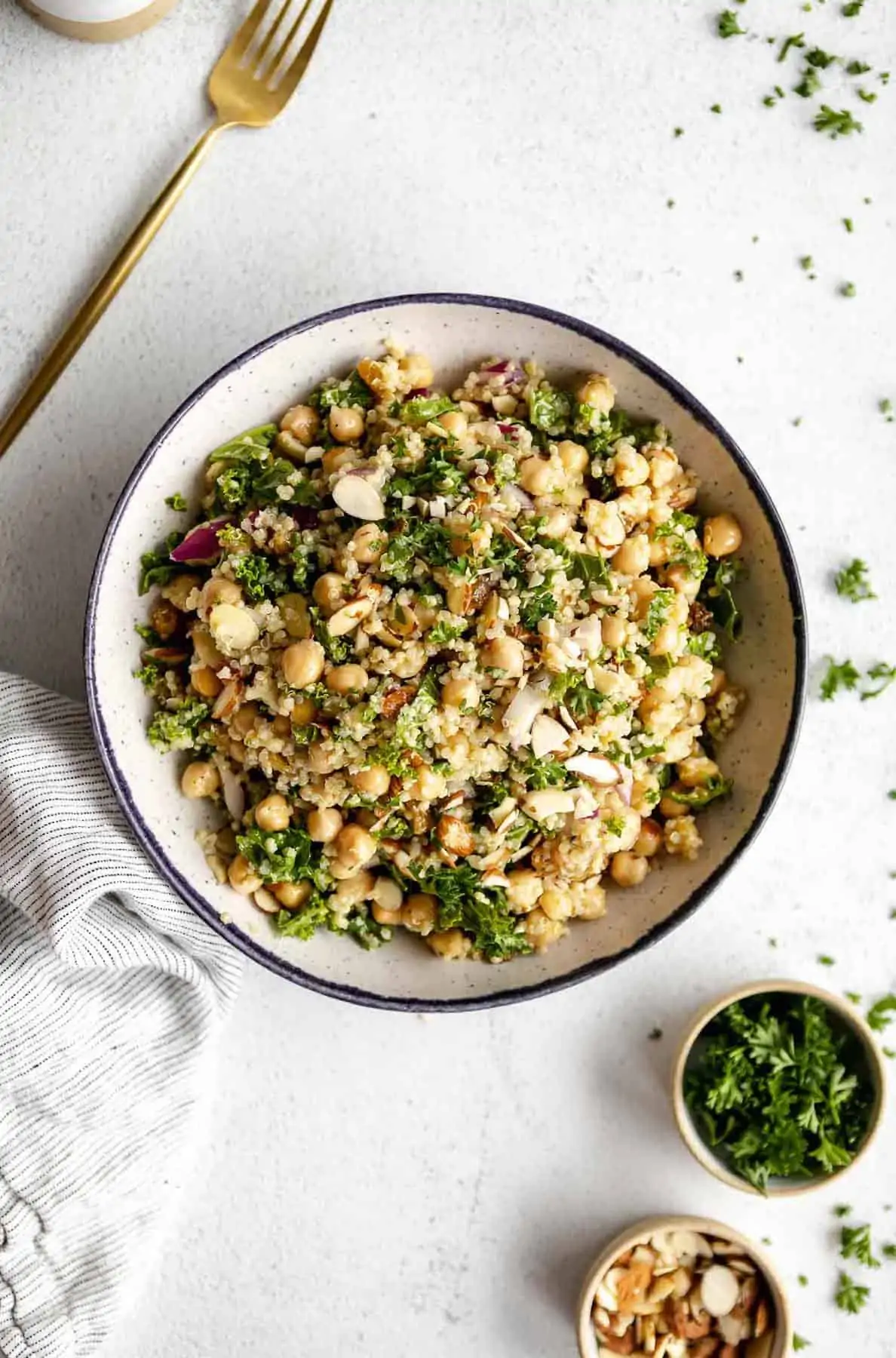 quinoa chickpea salad in a bowl with parsley and a fork on the side