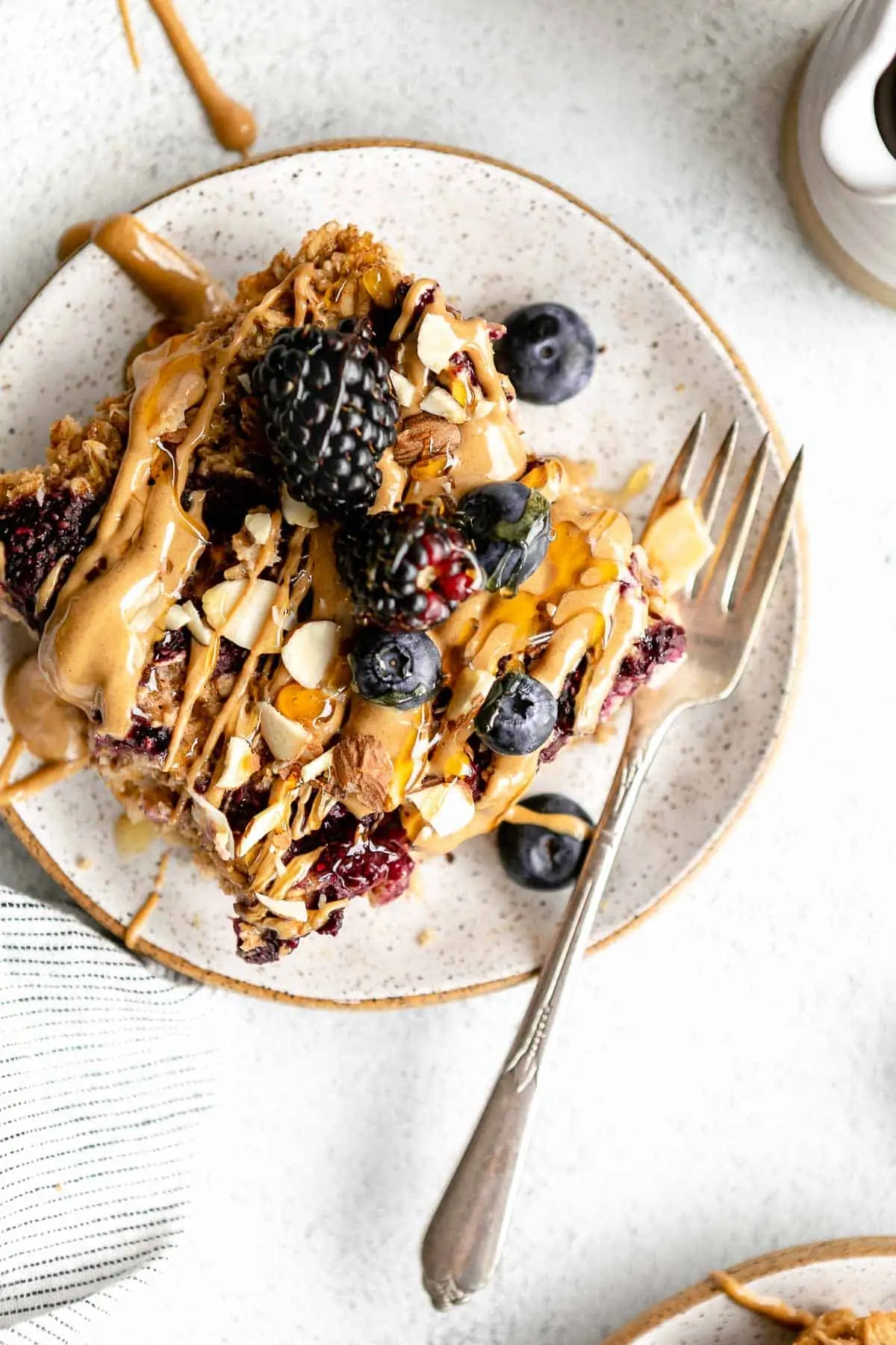 vegan baked oatmeal on a plate with berries and peanut butter