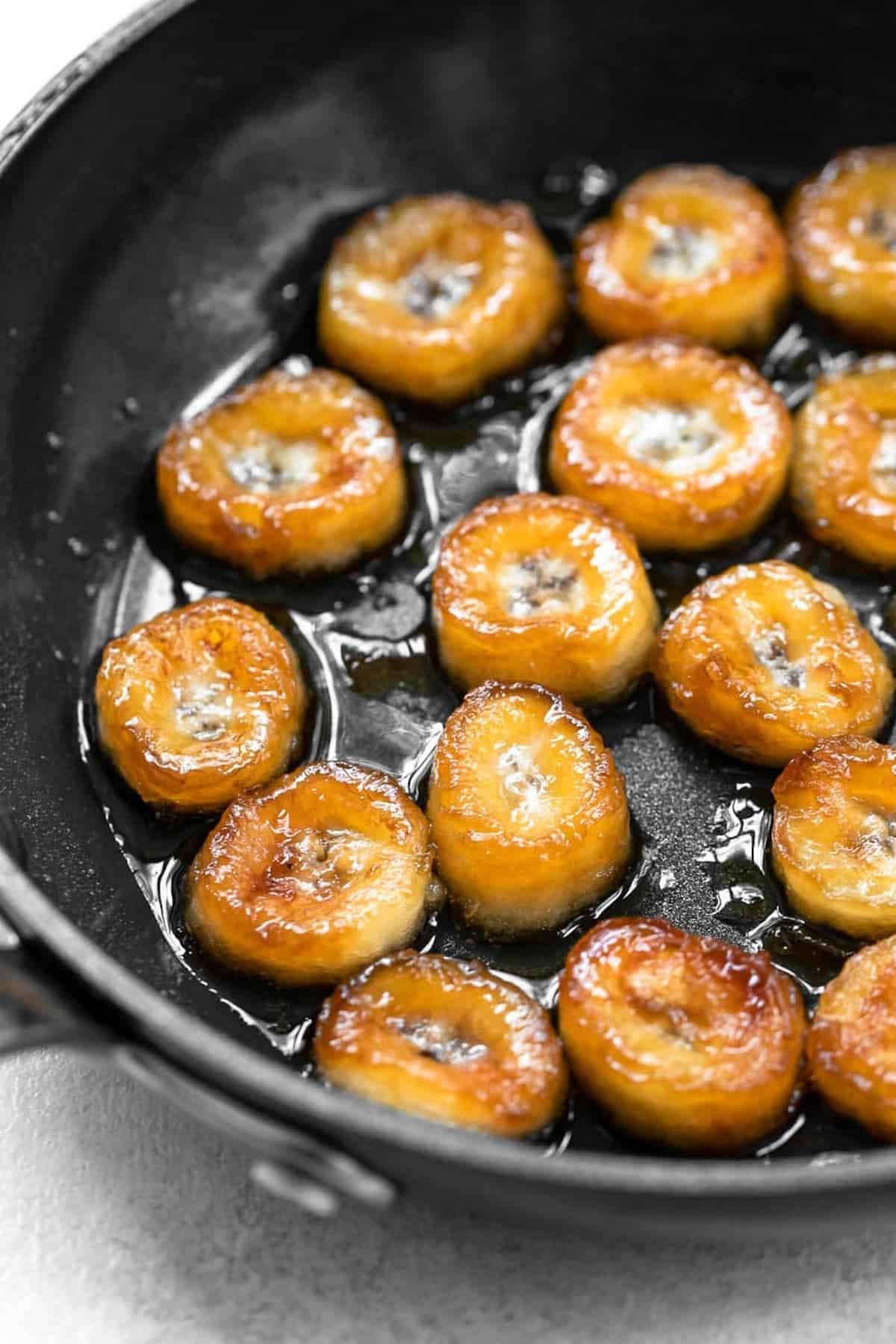 Caramelized bananas in a black pan.