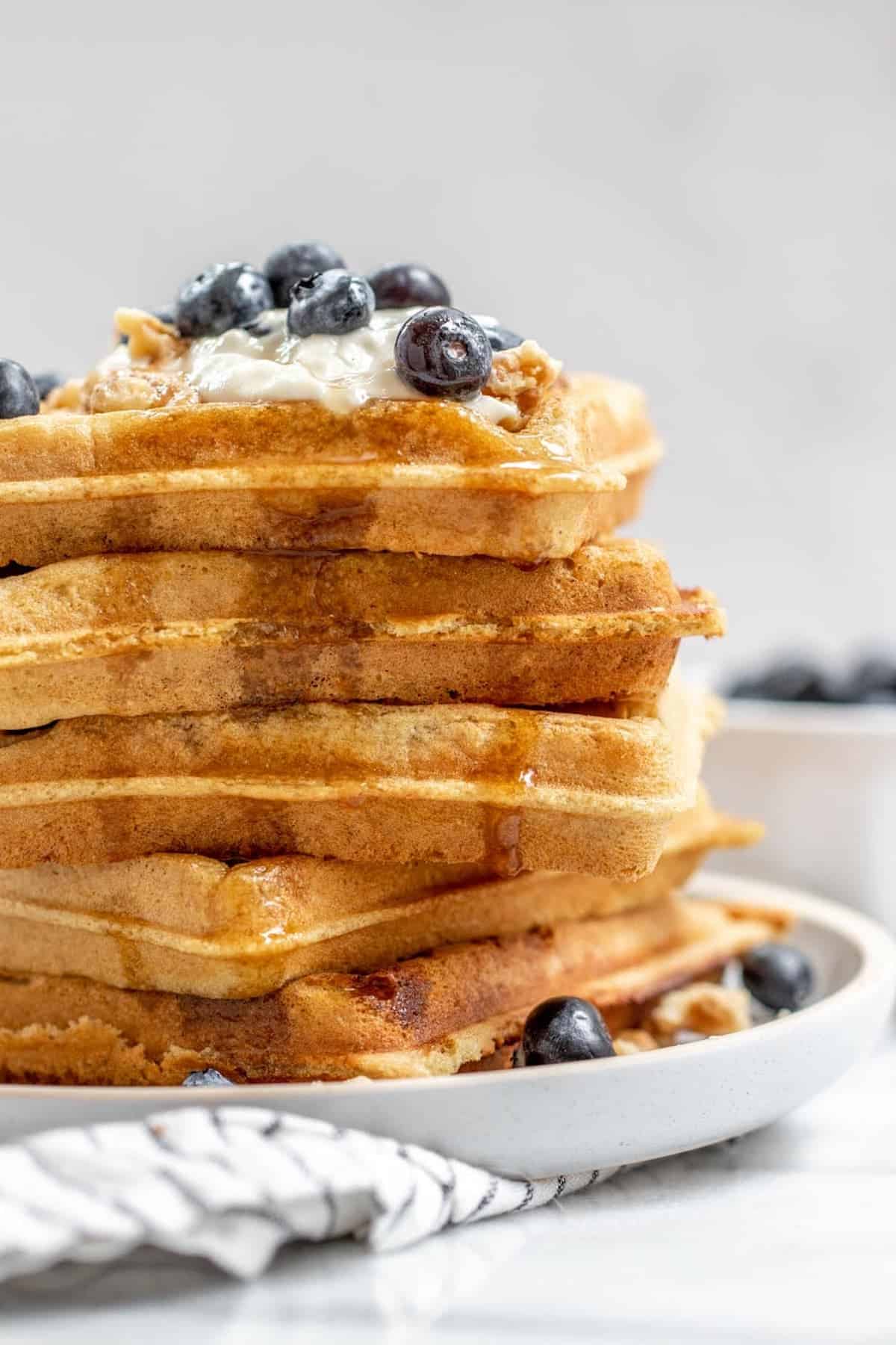 Tall stack of vegan almond flour waffles with berries on top.