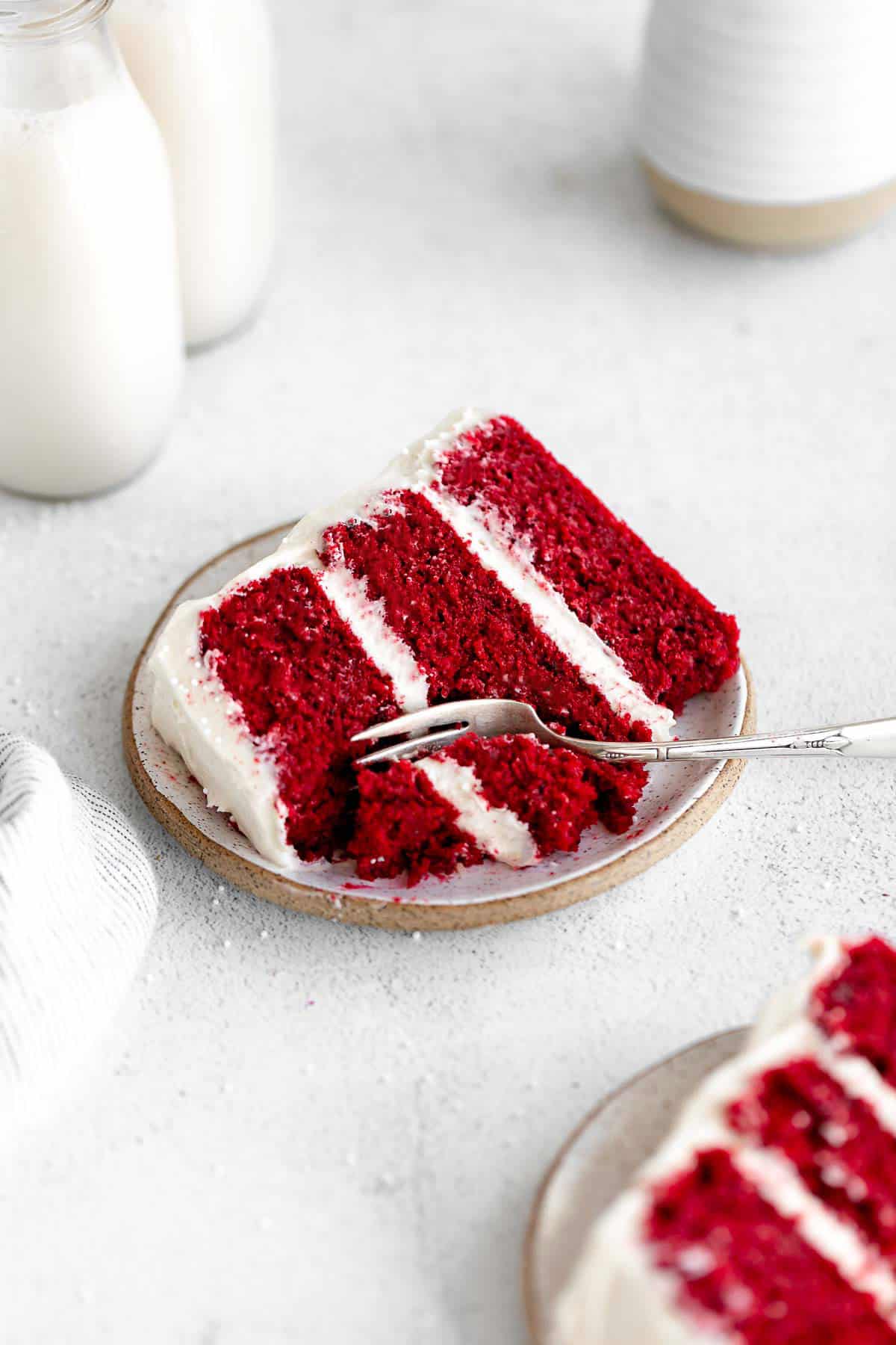 two slices of gluten free red velvet cake on plate with milk in the background