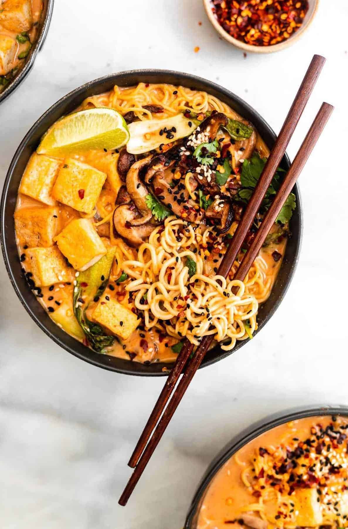 vegan curry ramen in a black bowl with noodles around the chopsticks