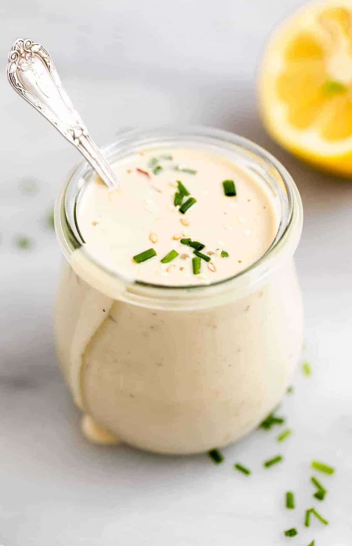 Glass jar with the tahini dressing dripping down the side.