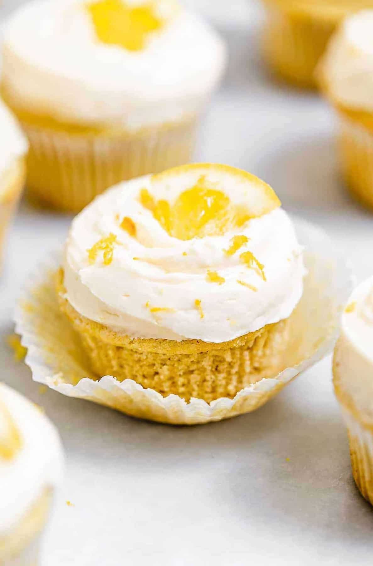 Vegan cupcakes arranged on a white backdrop with lemon wedges on top. 