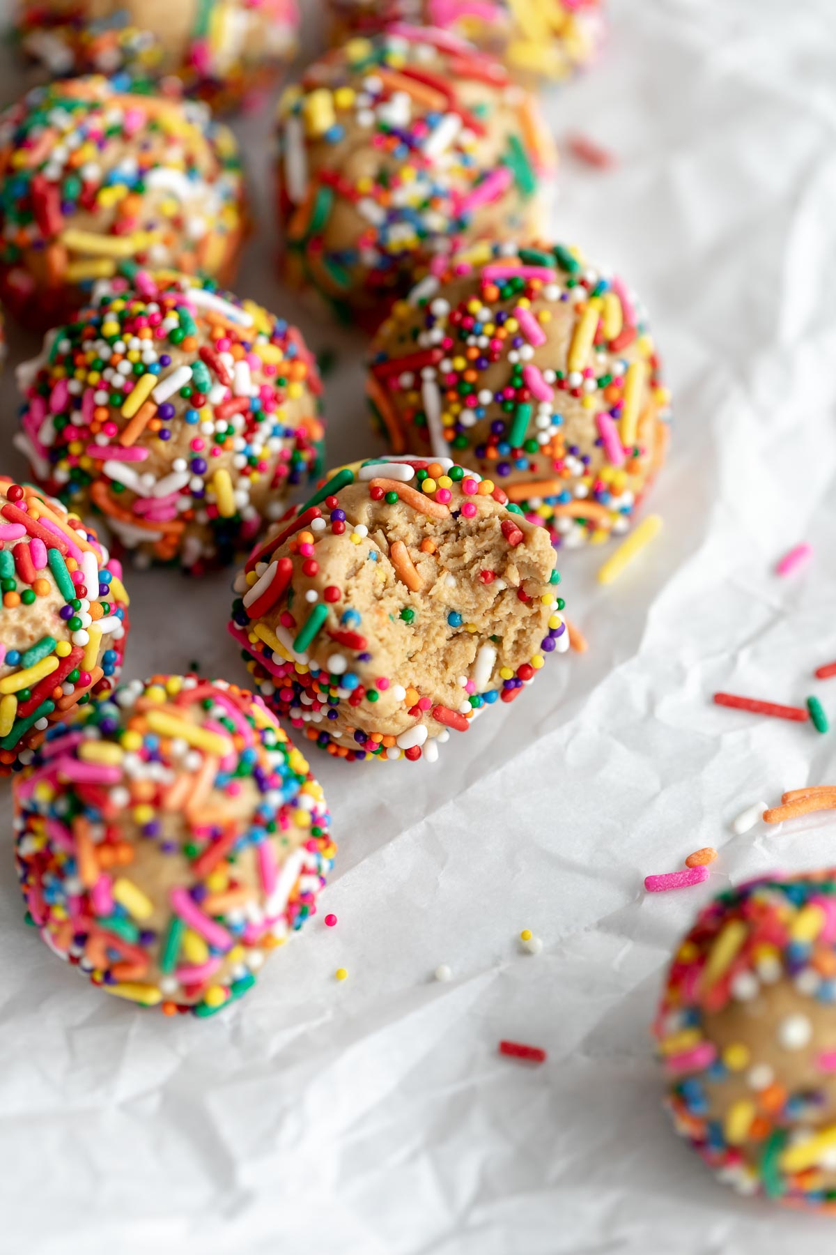 cake batter protein balls with rainbow sprinkles on parchment paper