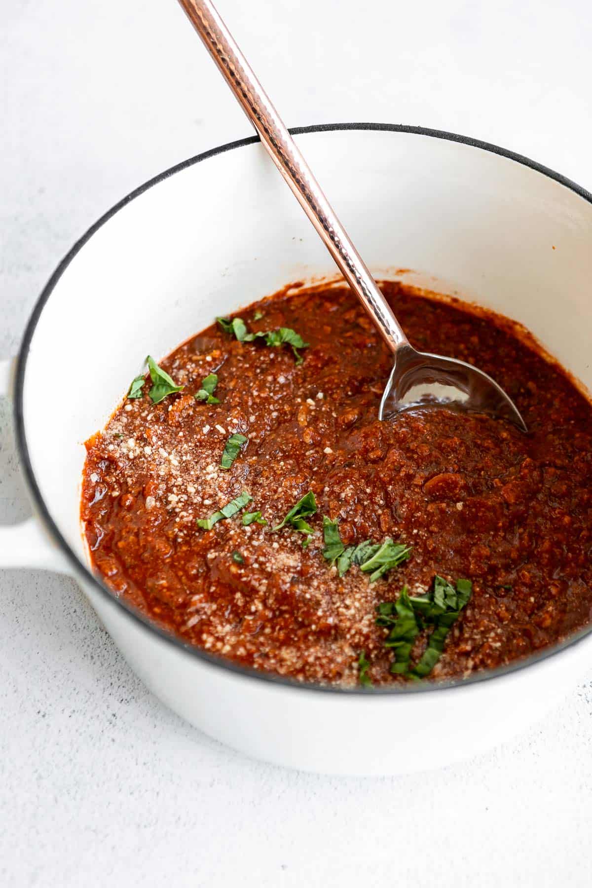 chicken bolognese sauce in a pot with a spoon on the side