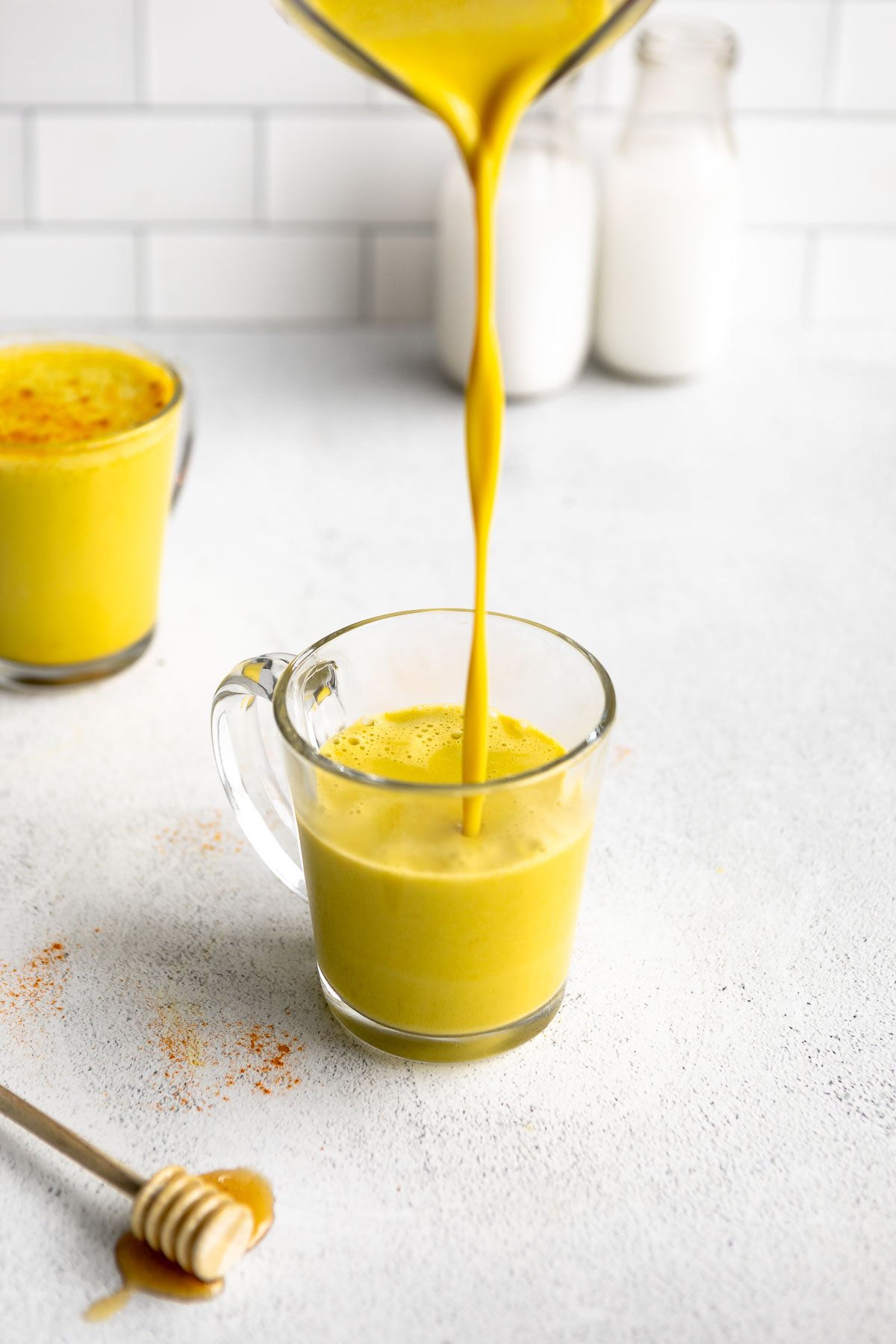 pouring the golden milk turmeric latte in a glass mug