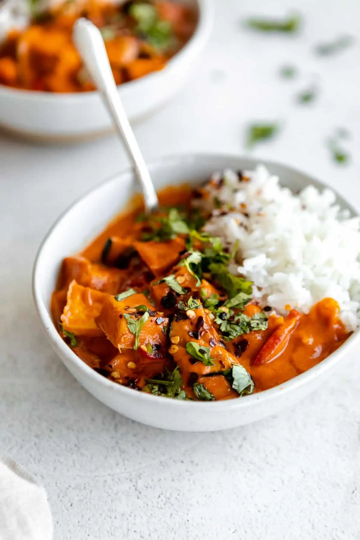vegan thai red tofu curry in a bowl with white rice and a spoon