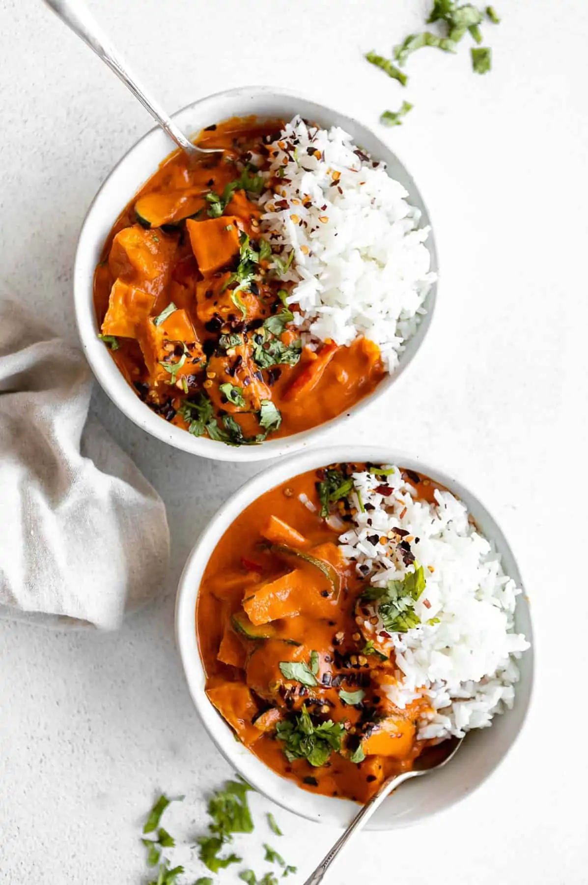 two bowls of thai red tofu curry with cilantro on top